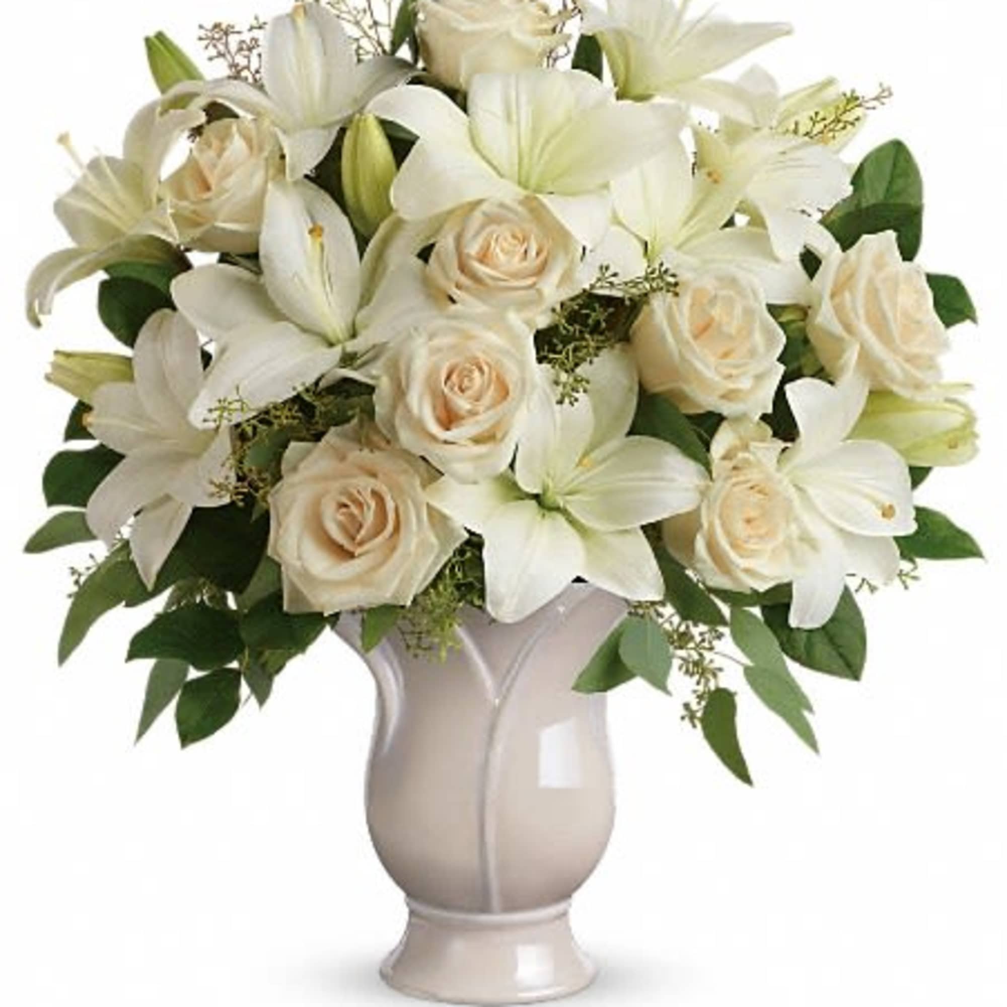 Arrangement of cream roses and white lilies in a white ceramic vase