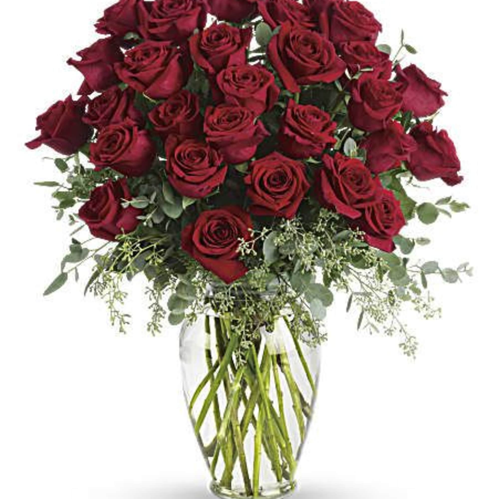 Tall arrangement of dark red roses in a clear glass vase