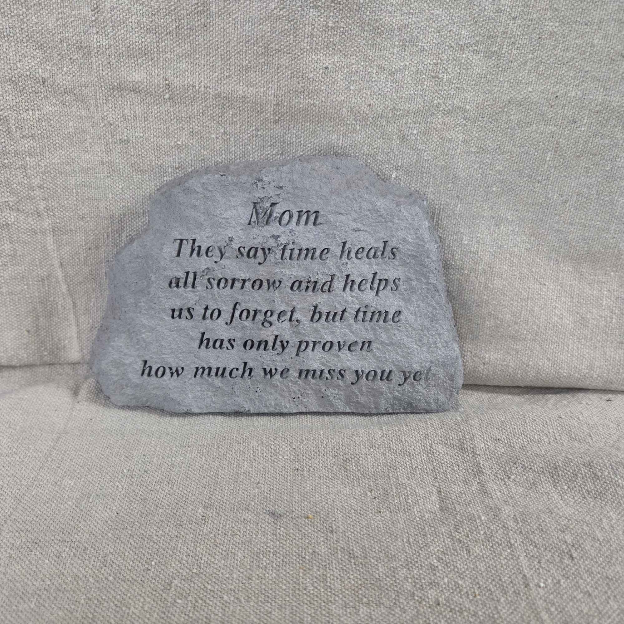 Gray memorial stone engraved with a Mom remembrance verse on a neutral fabric background.