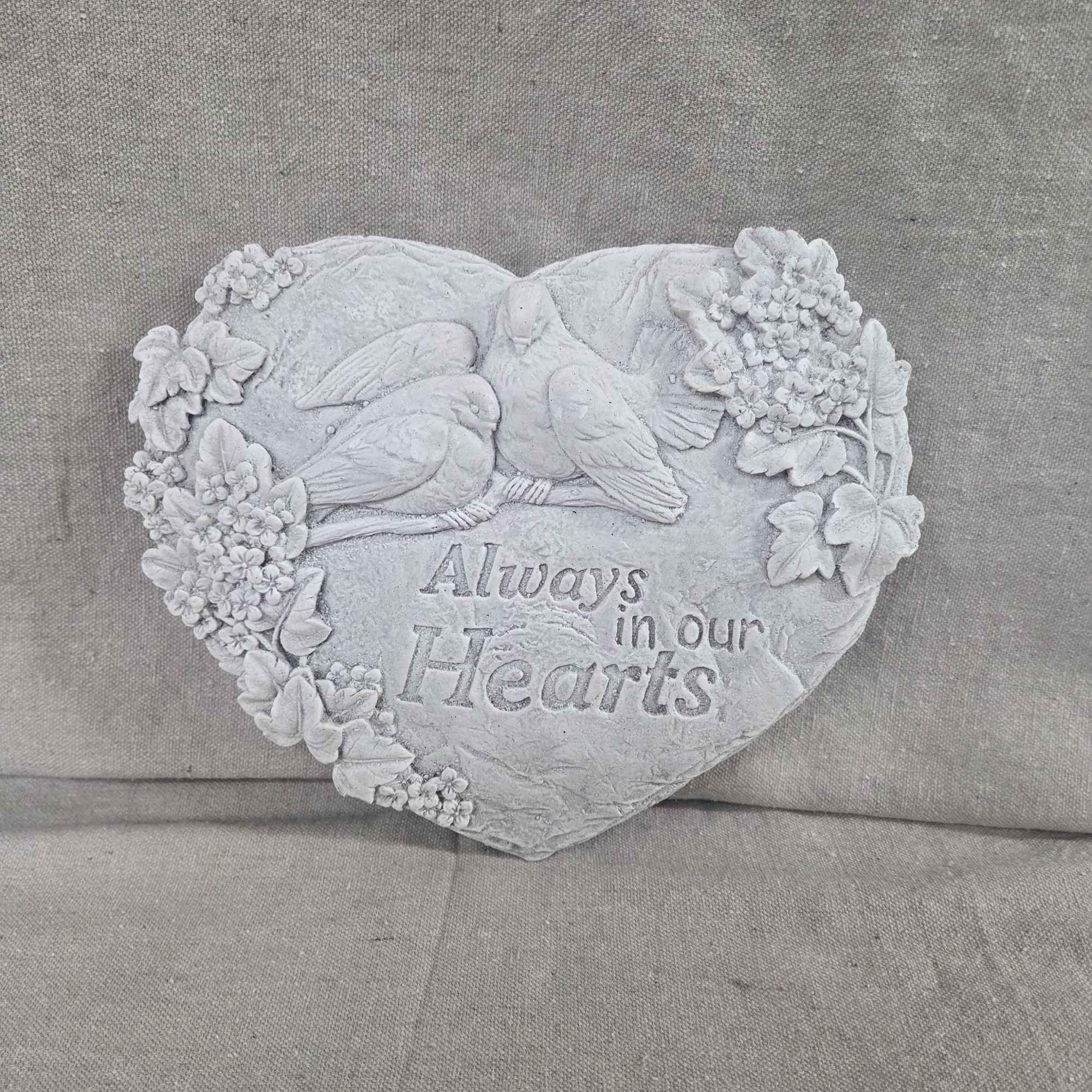 Heart-shaped stone memorial plaque with doves, carved flowers, and the words Always in our Hearts.