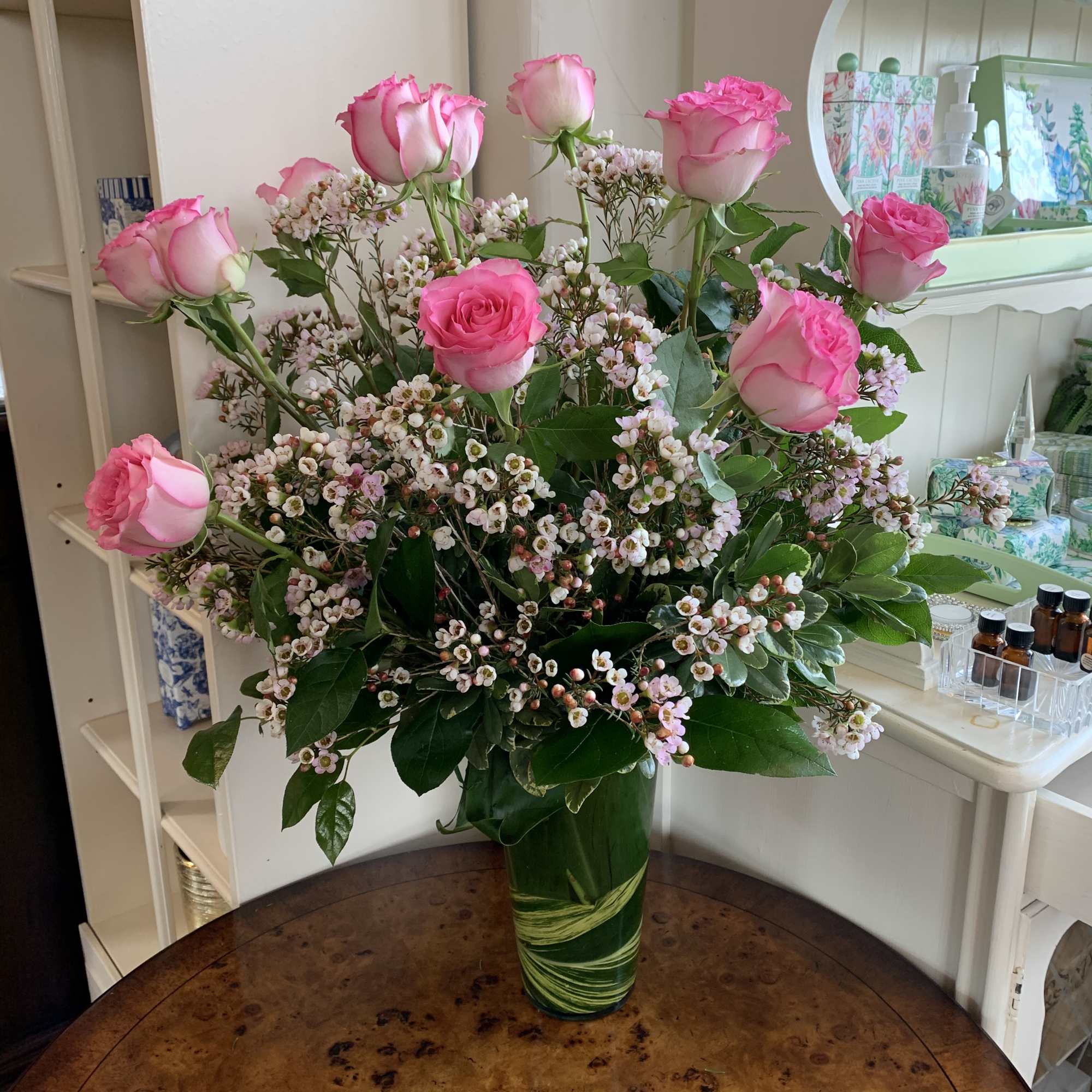 Pink roses in a green glass vase with small white filler flowers