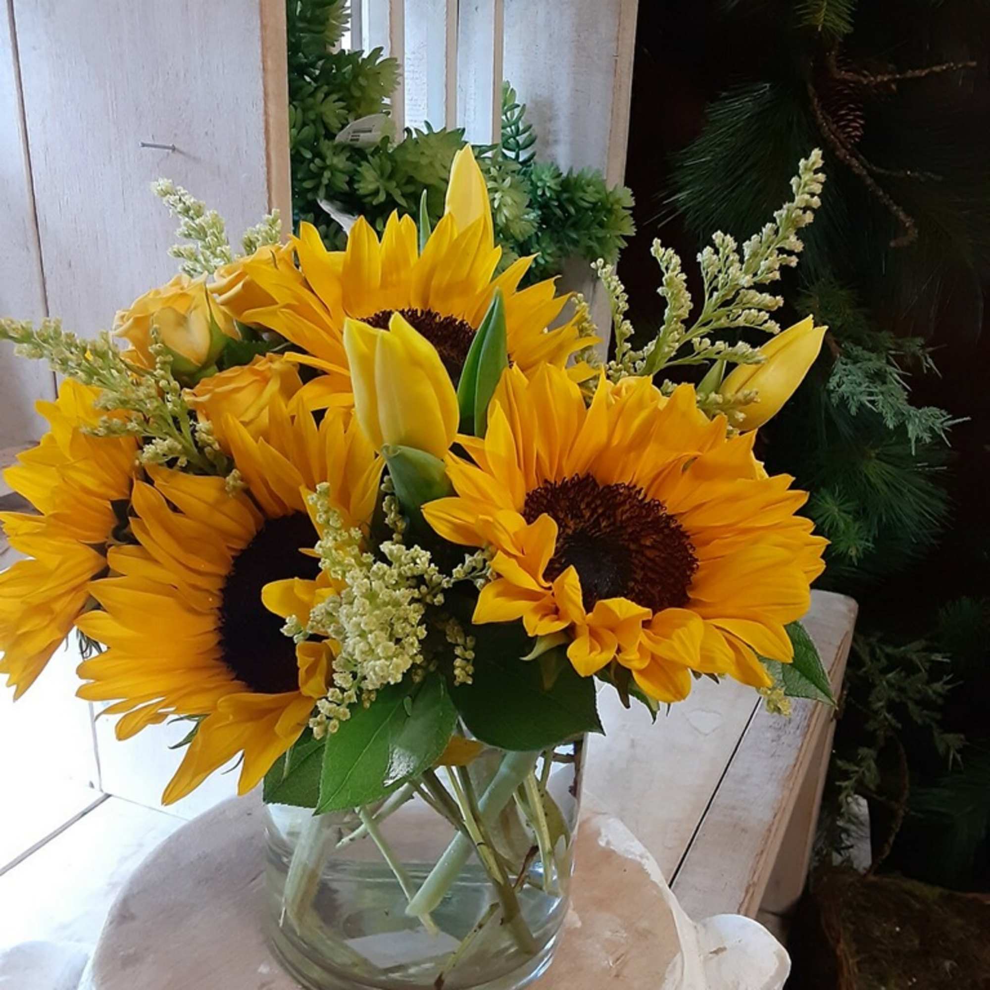 Bouquet of yellow sunflowers and tulips in a clear glass vase