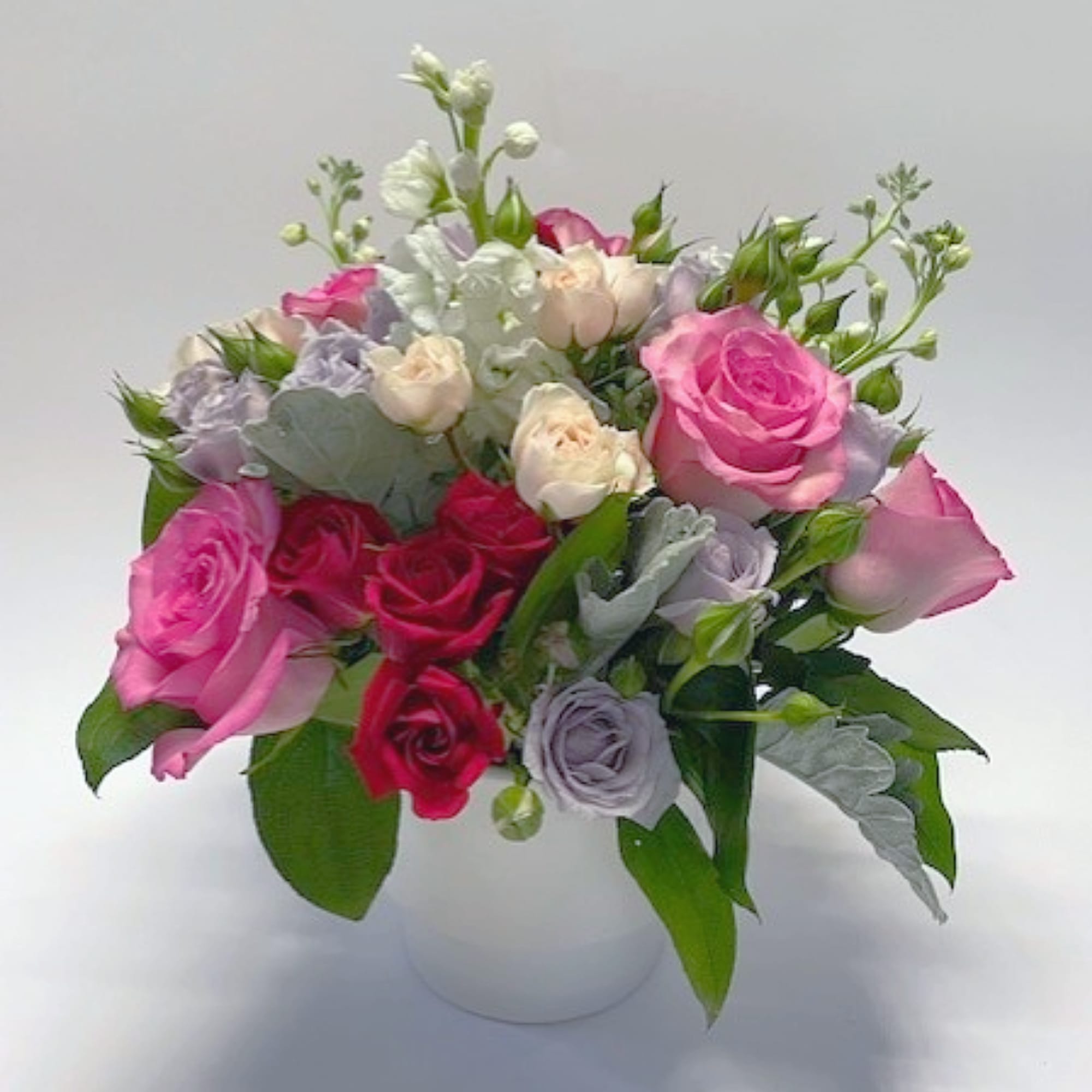 Mixed pink and lavender roses in a white vase