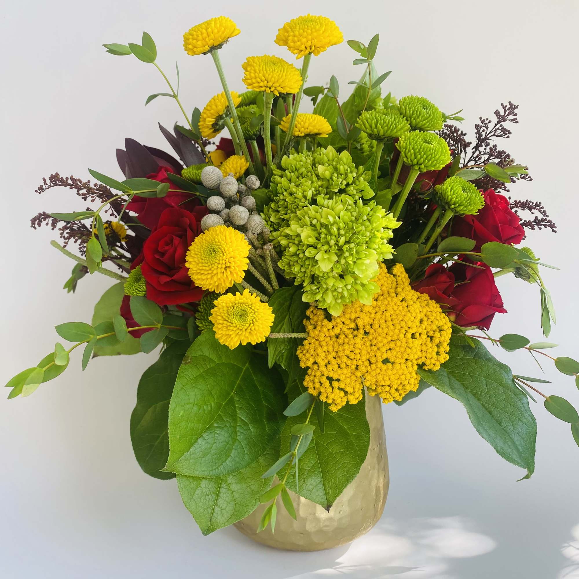 Mixed bouquet of red roses and yellow chrysanthemums in a gold vase