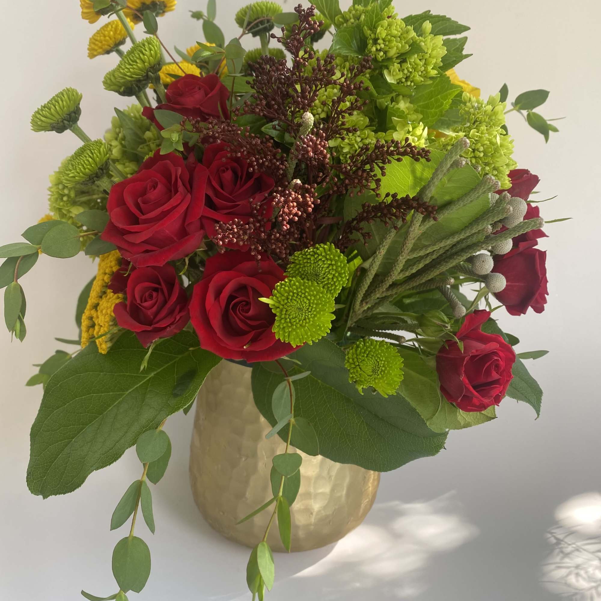 Bouquet of red roses and green chrysanthemums in a gold vase