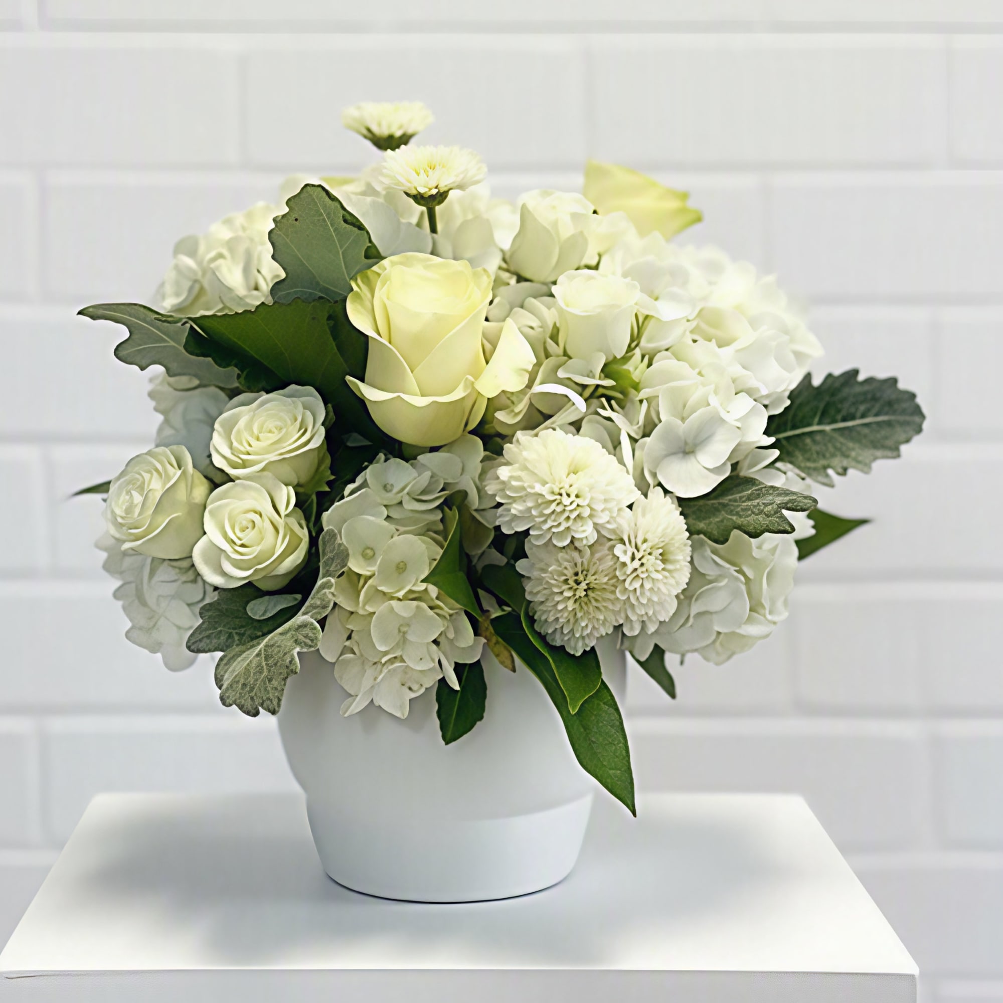 White floral arrangement in a white vase with roses and hydrangeas