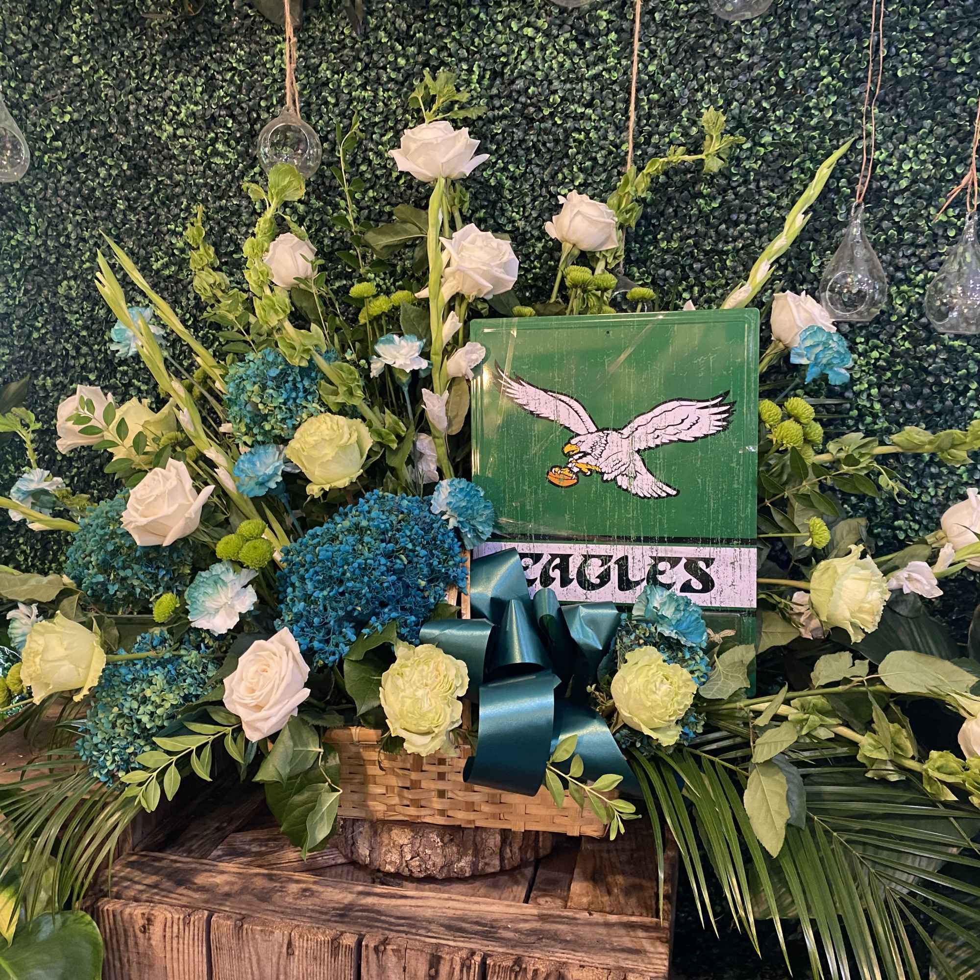 Large floral arrangement with white roses and blue hydrangeas around a green Eagles sign
