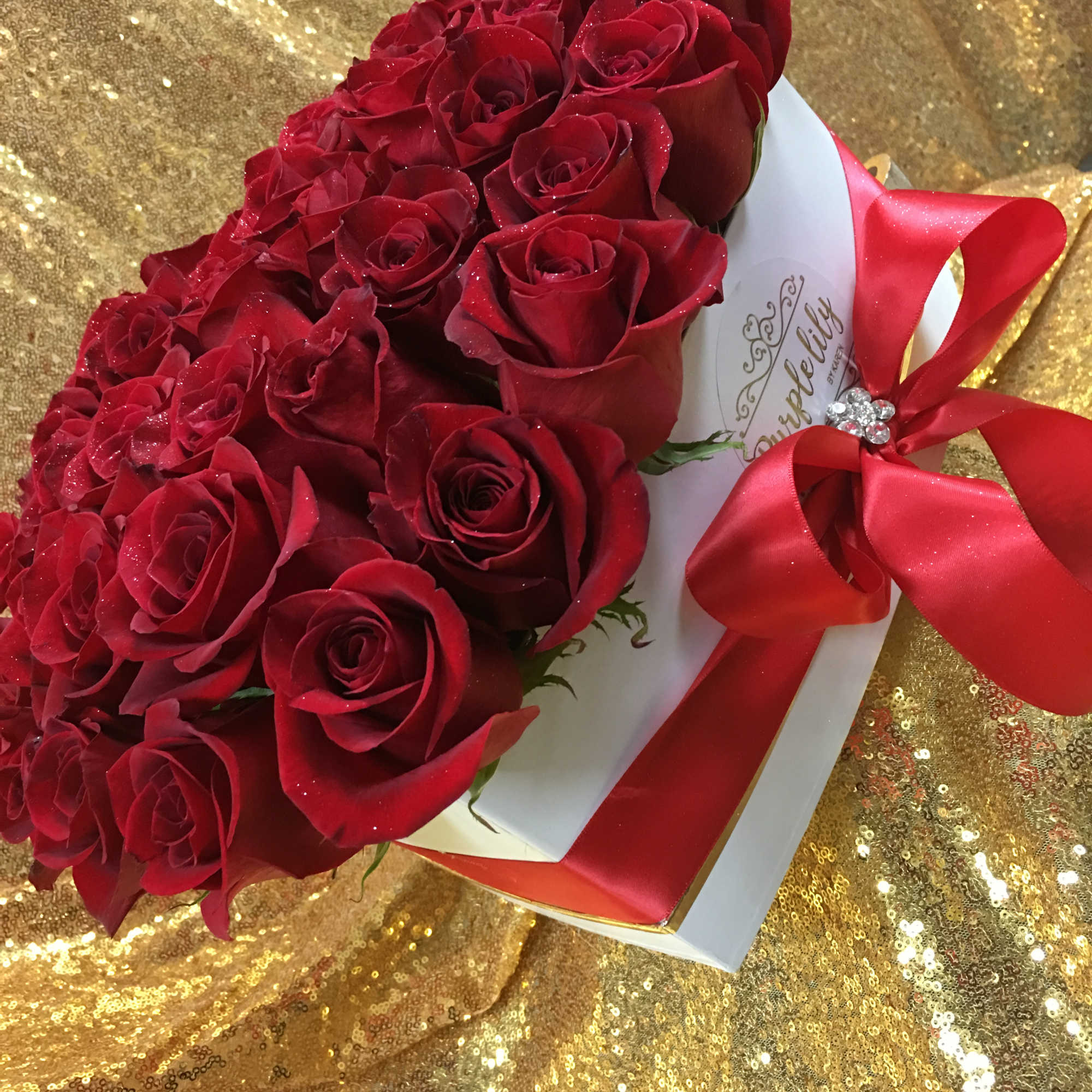 Bouquet of red roses wrapped with a red ribbon on a gold background