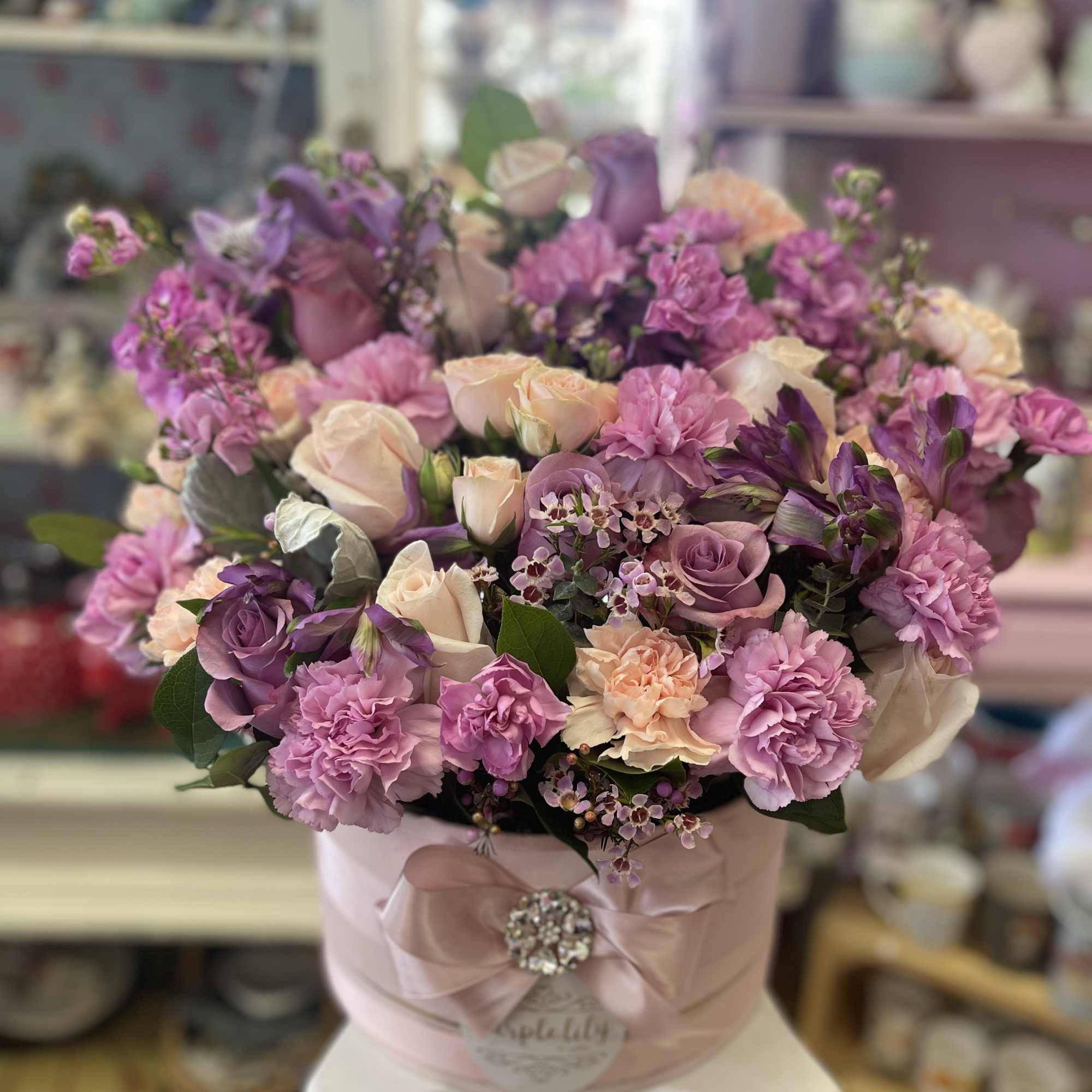 Pink and lavender bouquet in a round hatbox with a ribbon