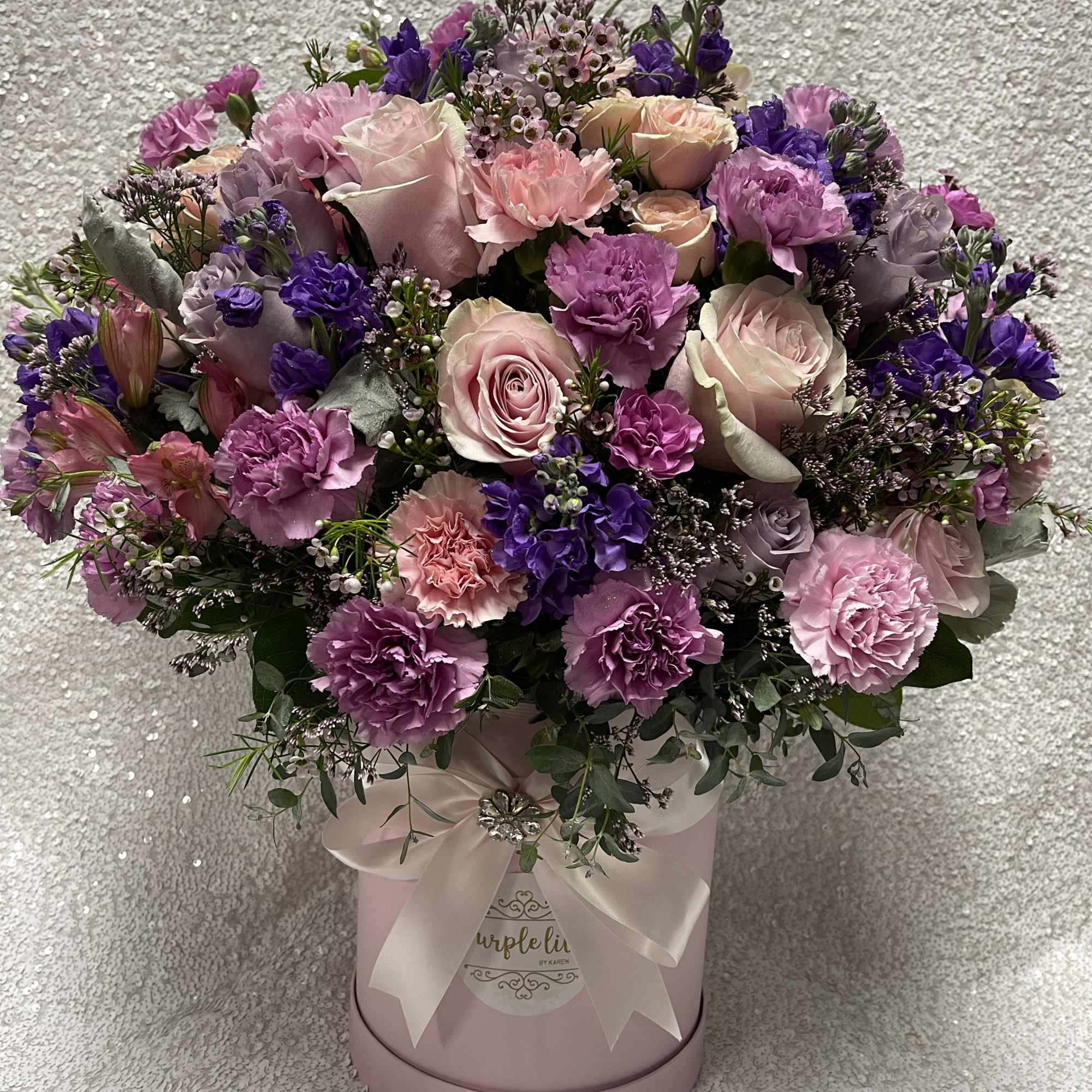 Pink and purple bouquet in a round pink hat box with ribbon
