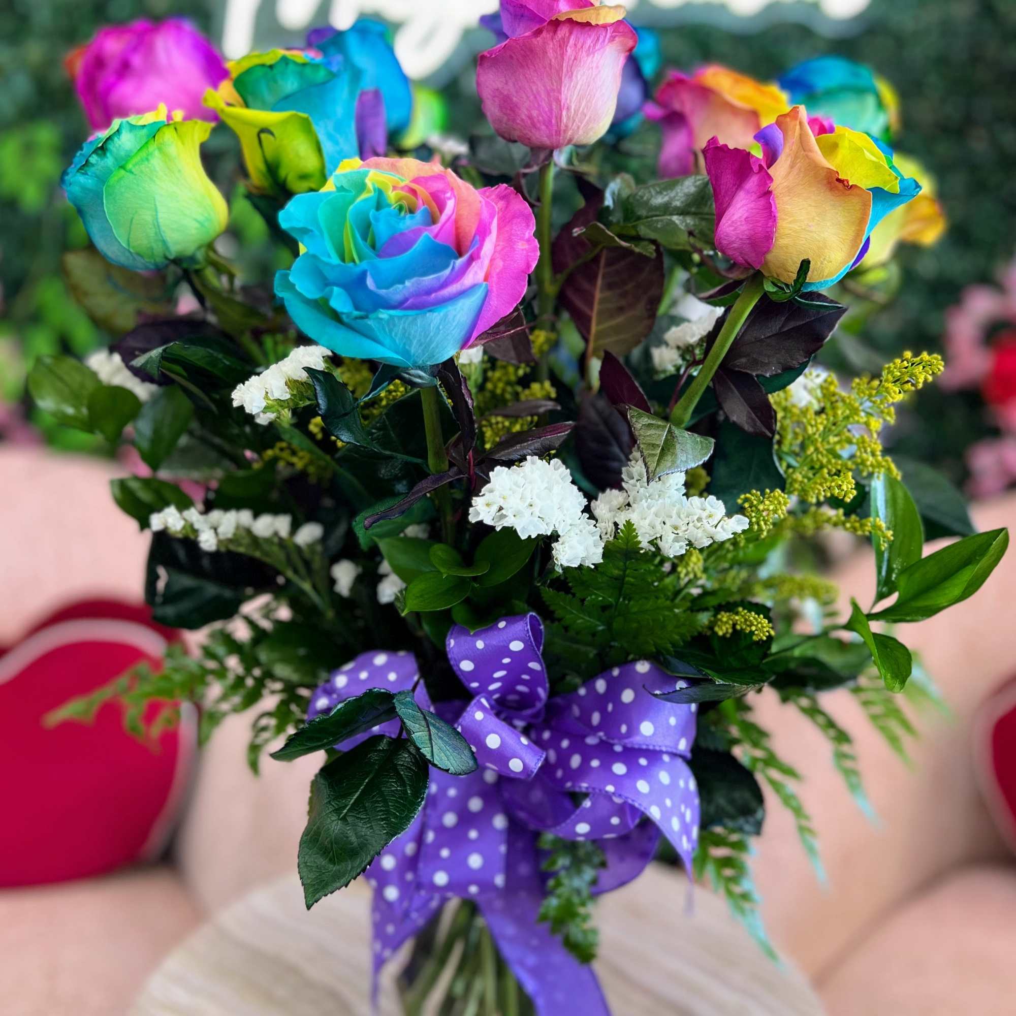 Bouquet of rainbow-colored roses tied with a purple polka-dot ribbon