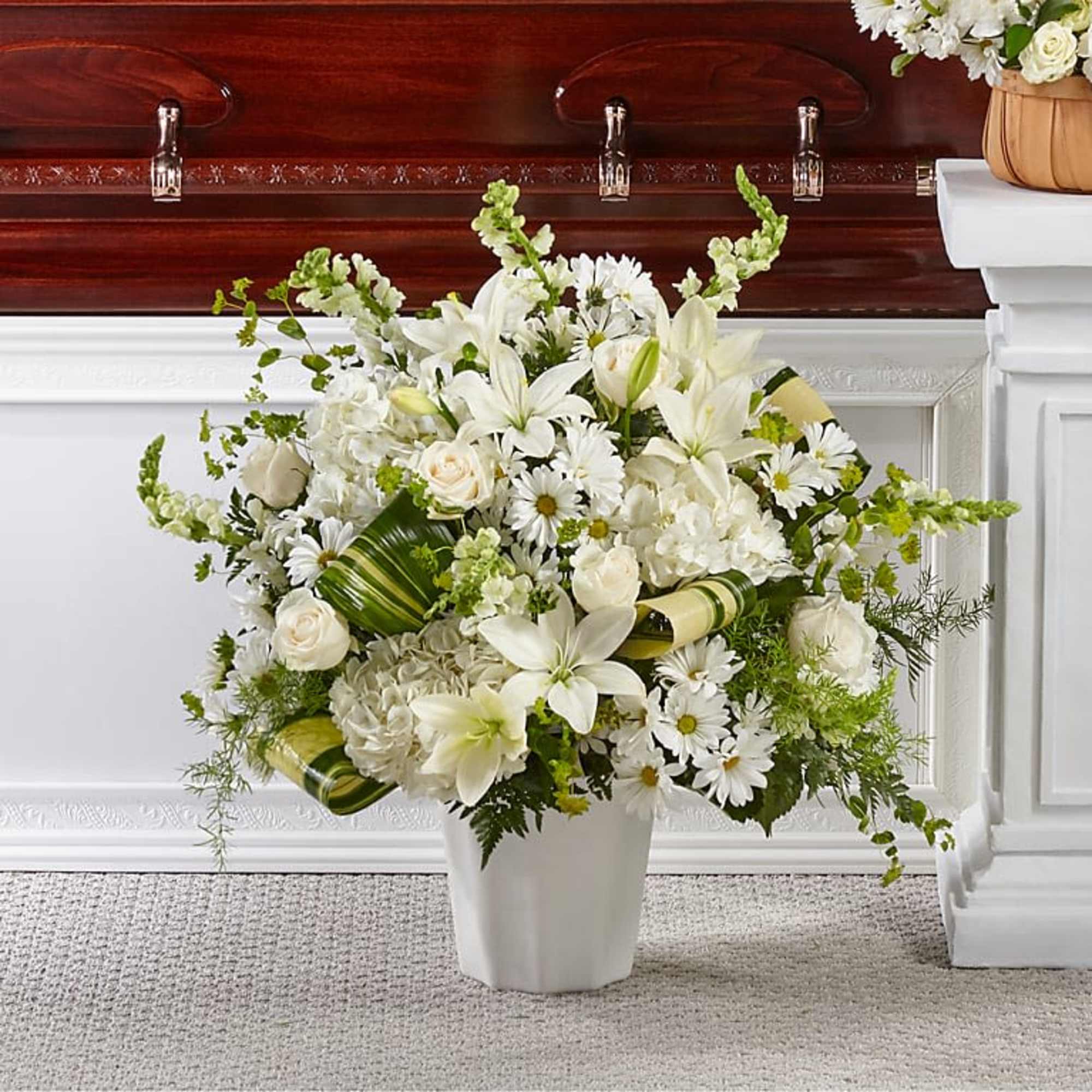 White floral arrangement in a white vase with lilies and daisies