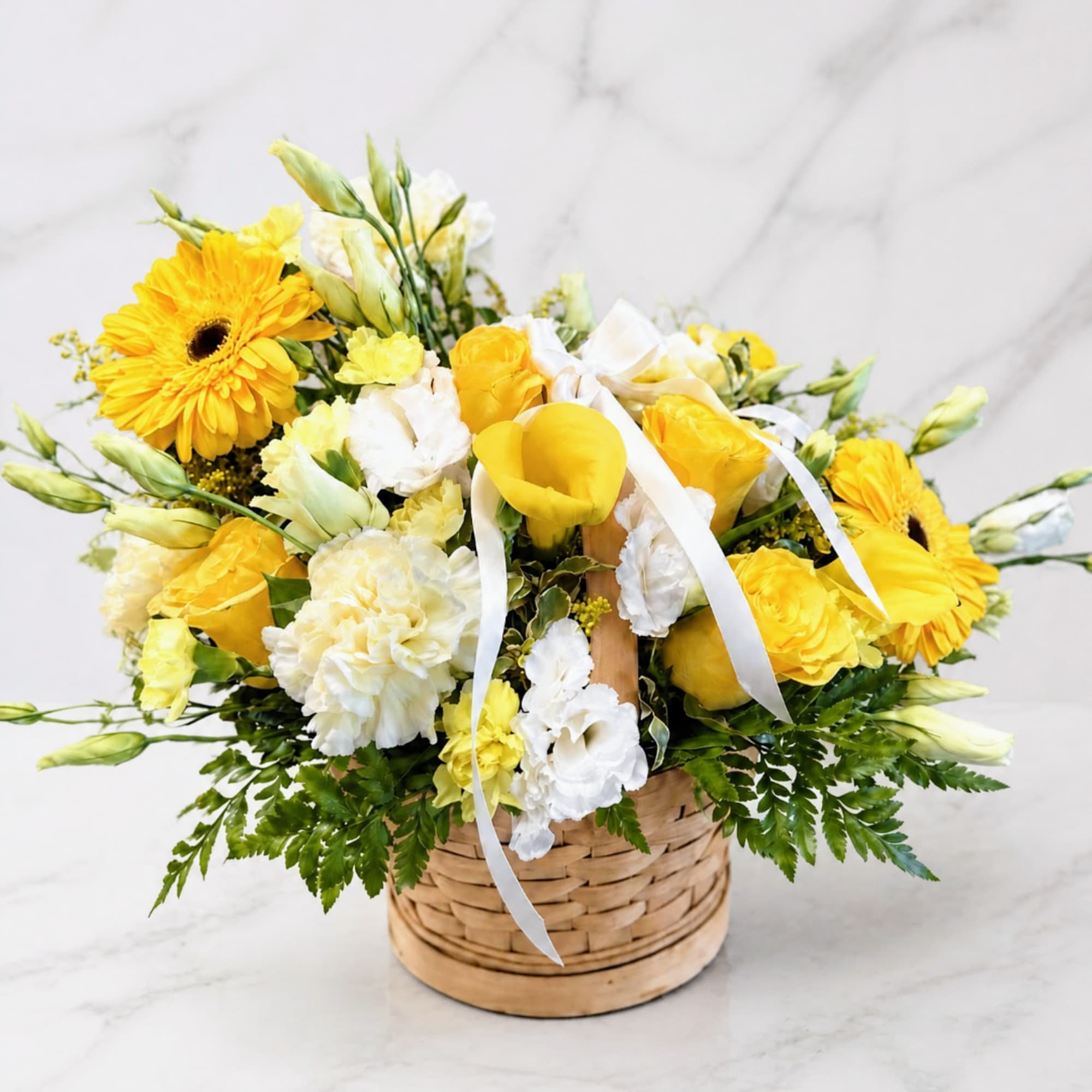 Yellow and white flower arrangement in a woven basket with ribbon