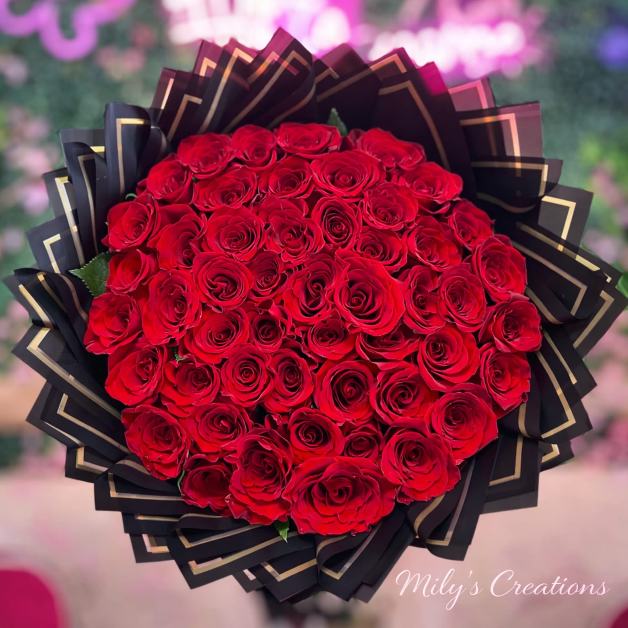 Large bouquet of red roses wrapped in black and gold decorative paper