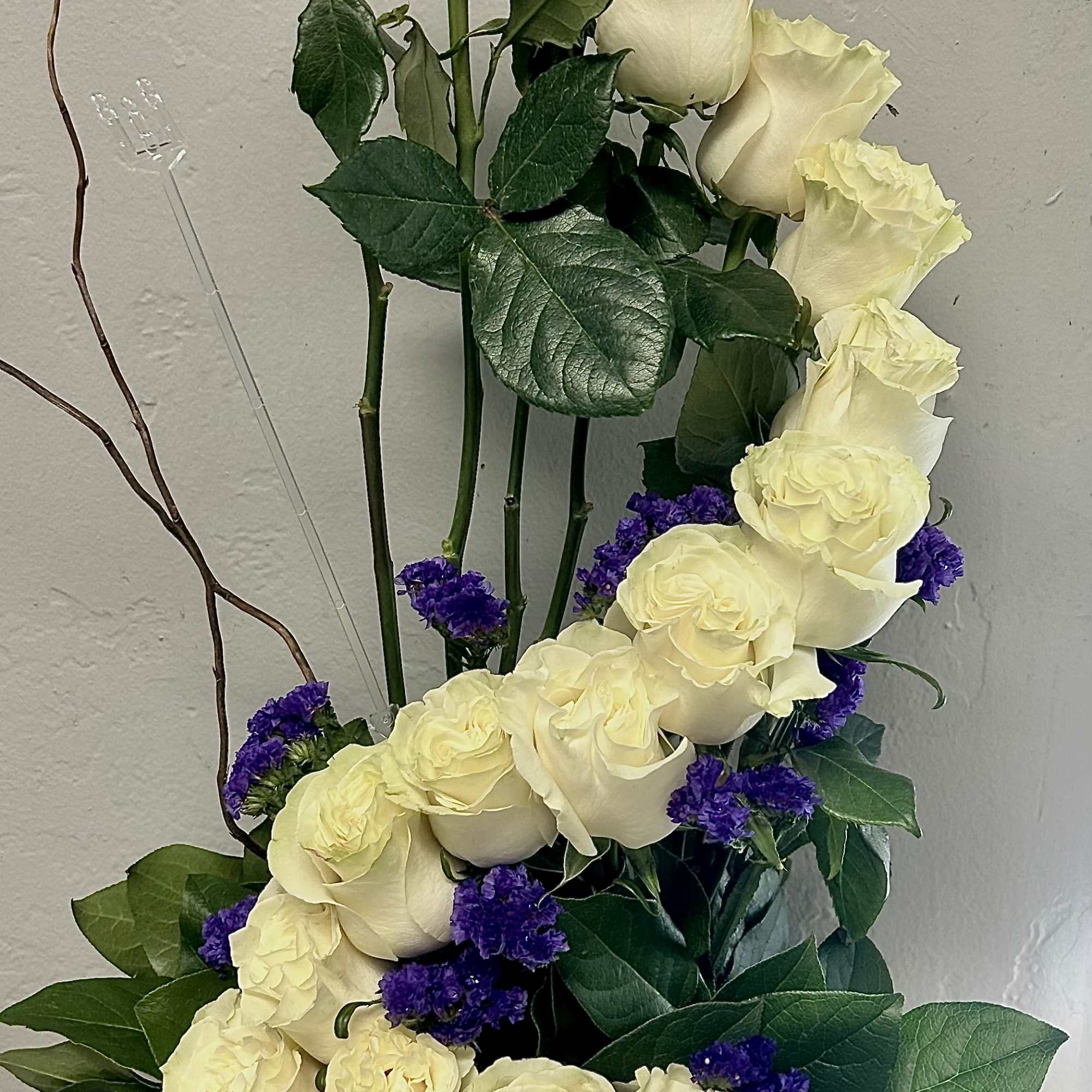 Tall arrangement of cream roses with purple filler flowers