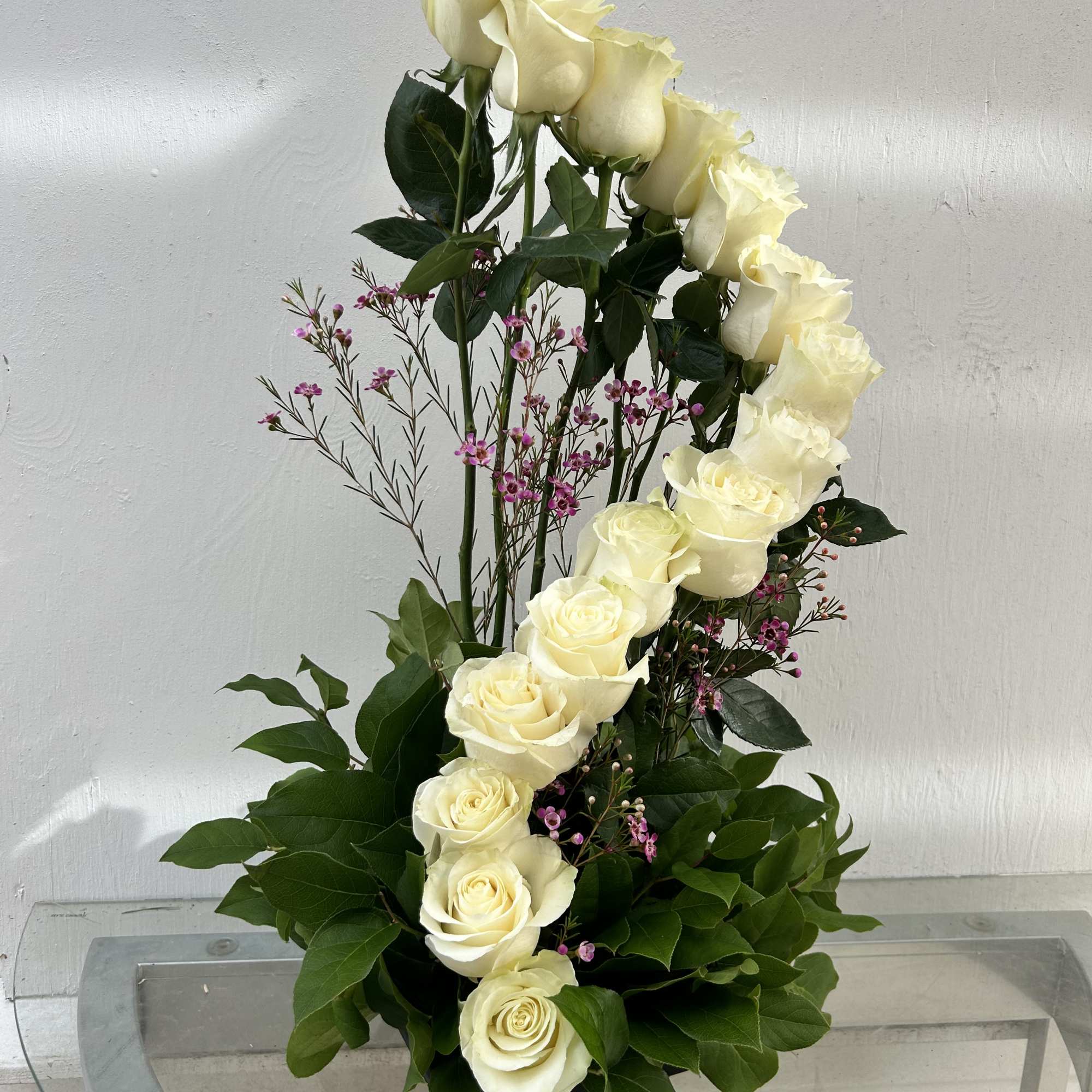 Tall arrangement of white roses with small pink filler flowers