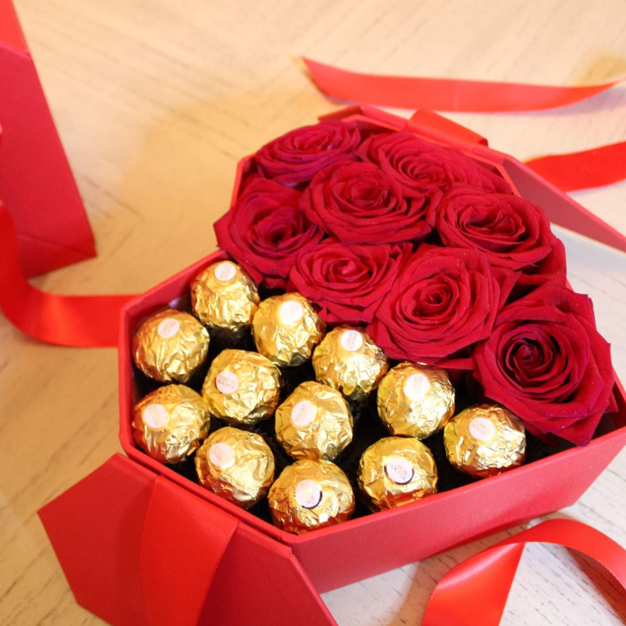 Red roses and gold-wrapped chocolates in a red gift box