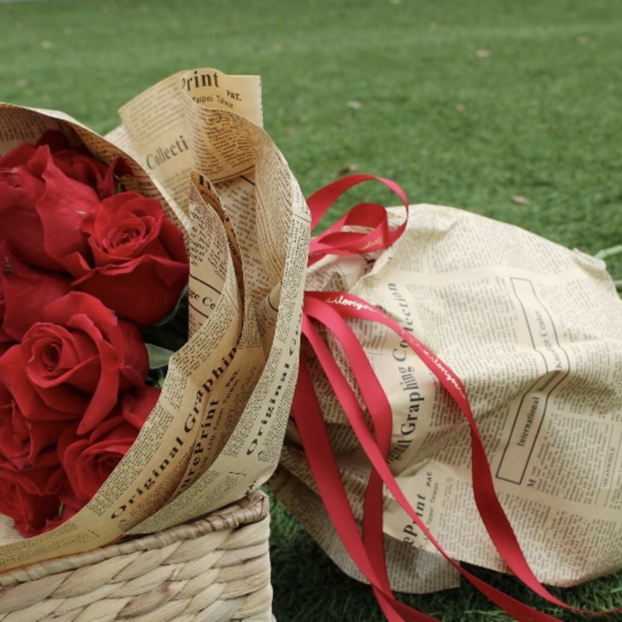 Bouquet of red roses wrapped in newspaper-style paper with a red ribbon