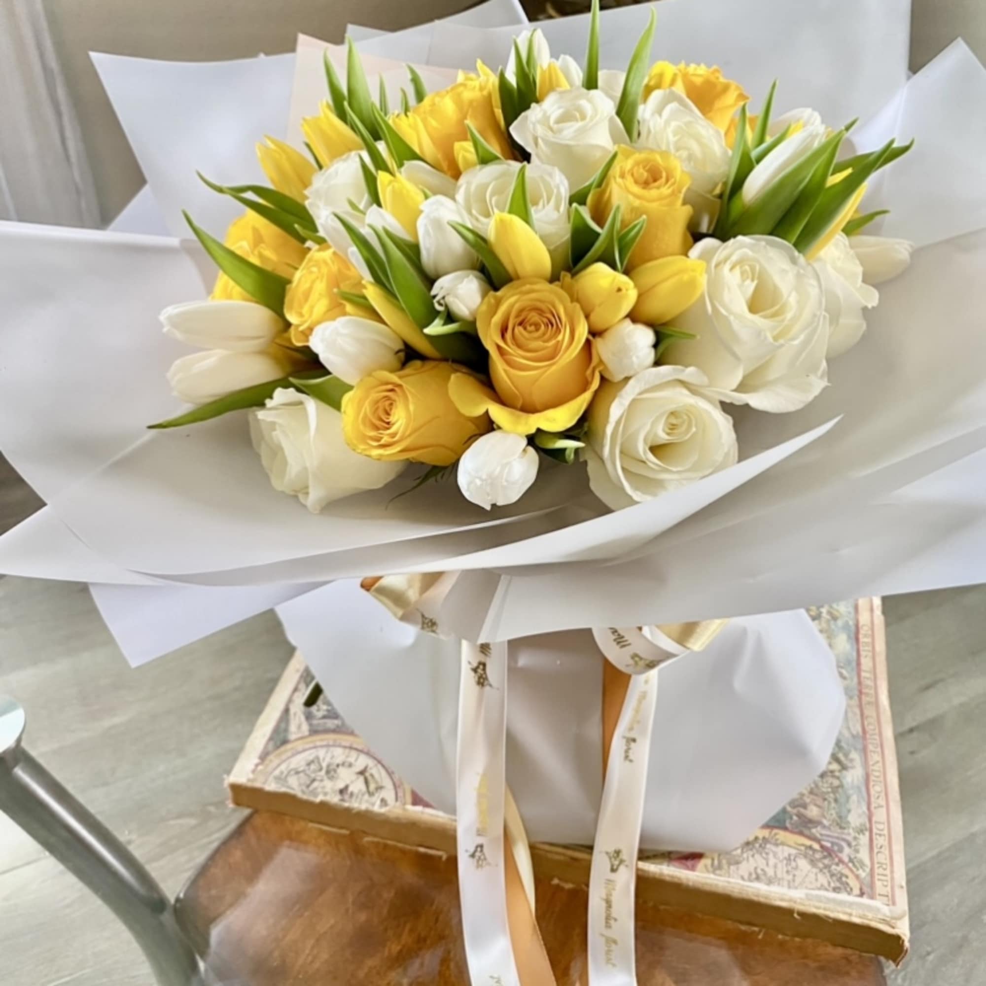 Bouquet of yellow and white roses with white tulips wrapped in white paper
