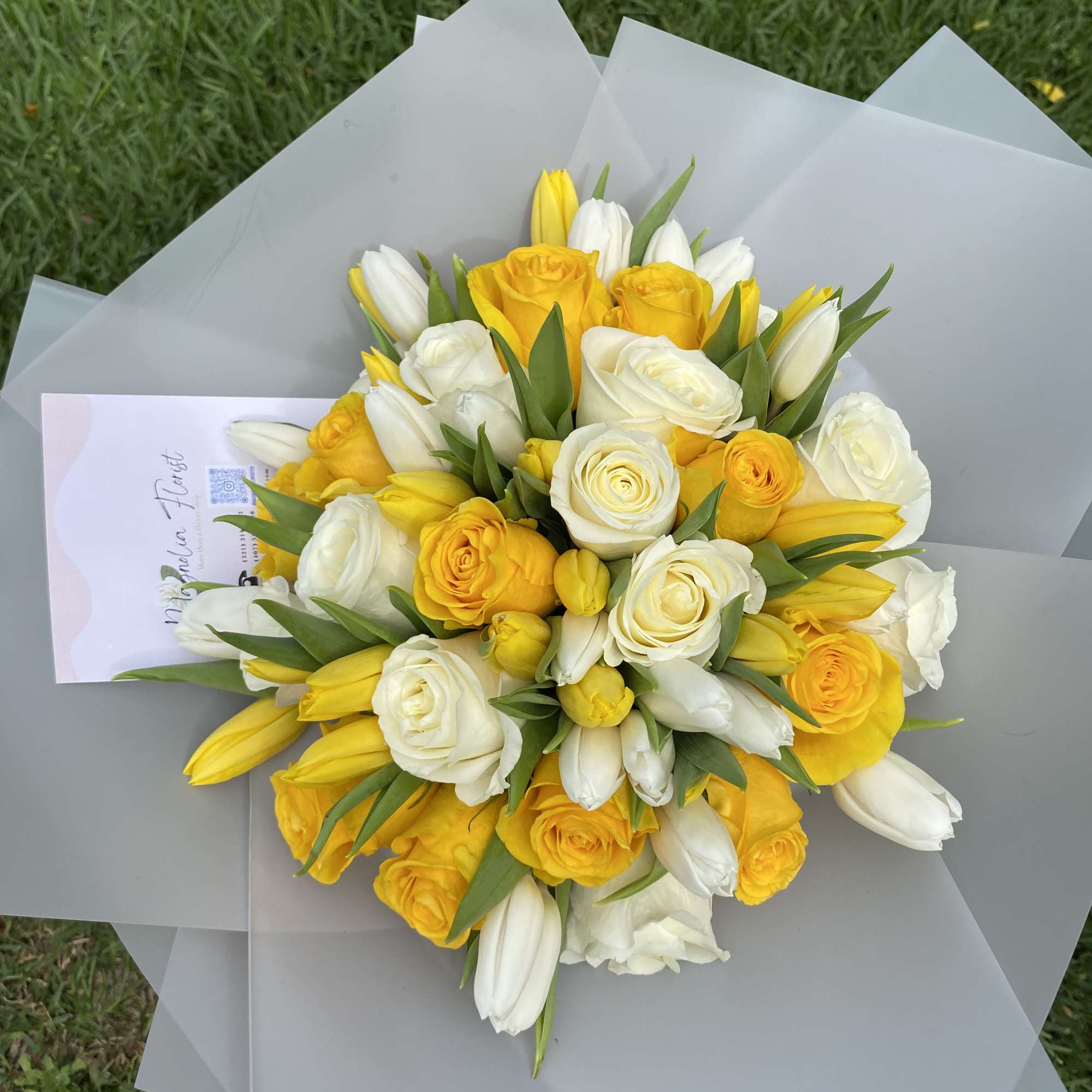 Bouquet of yellow and white roses with tulips wrapped in gray paper