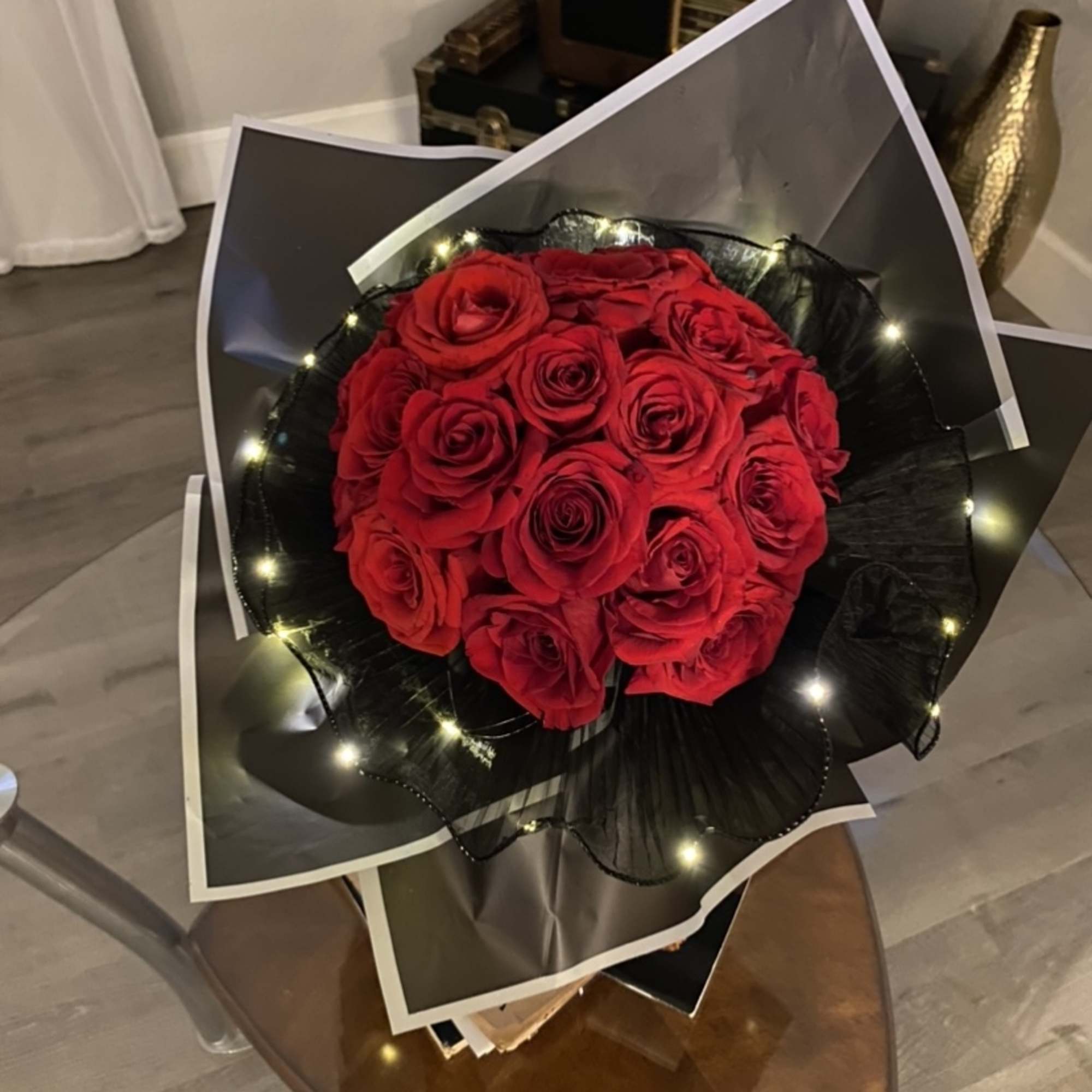 Bouquet of red roses wrapped in black paper with small lights