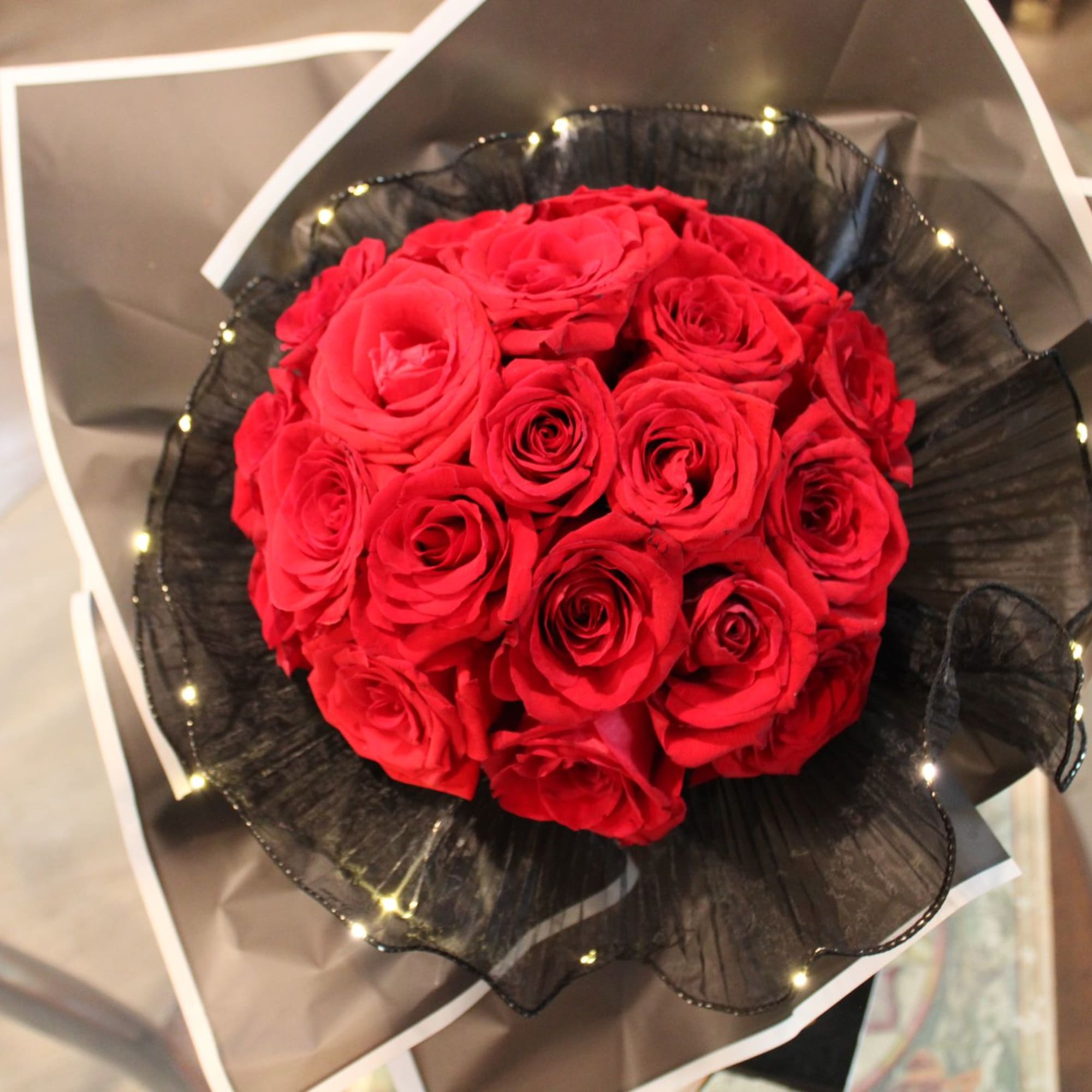 Bouquet of red roses wrapped in black paper with white trim