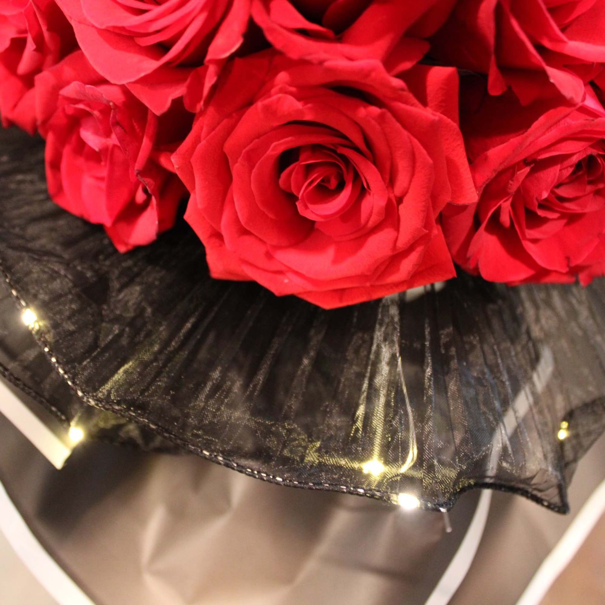 Bouquet of red roses wrapped in black mesh with tiny lights