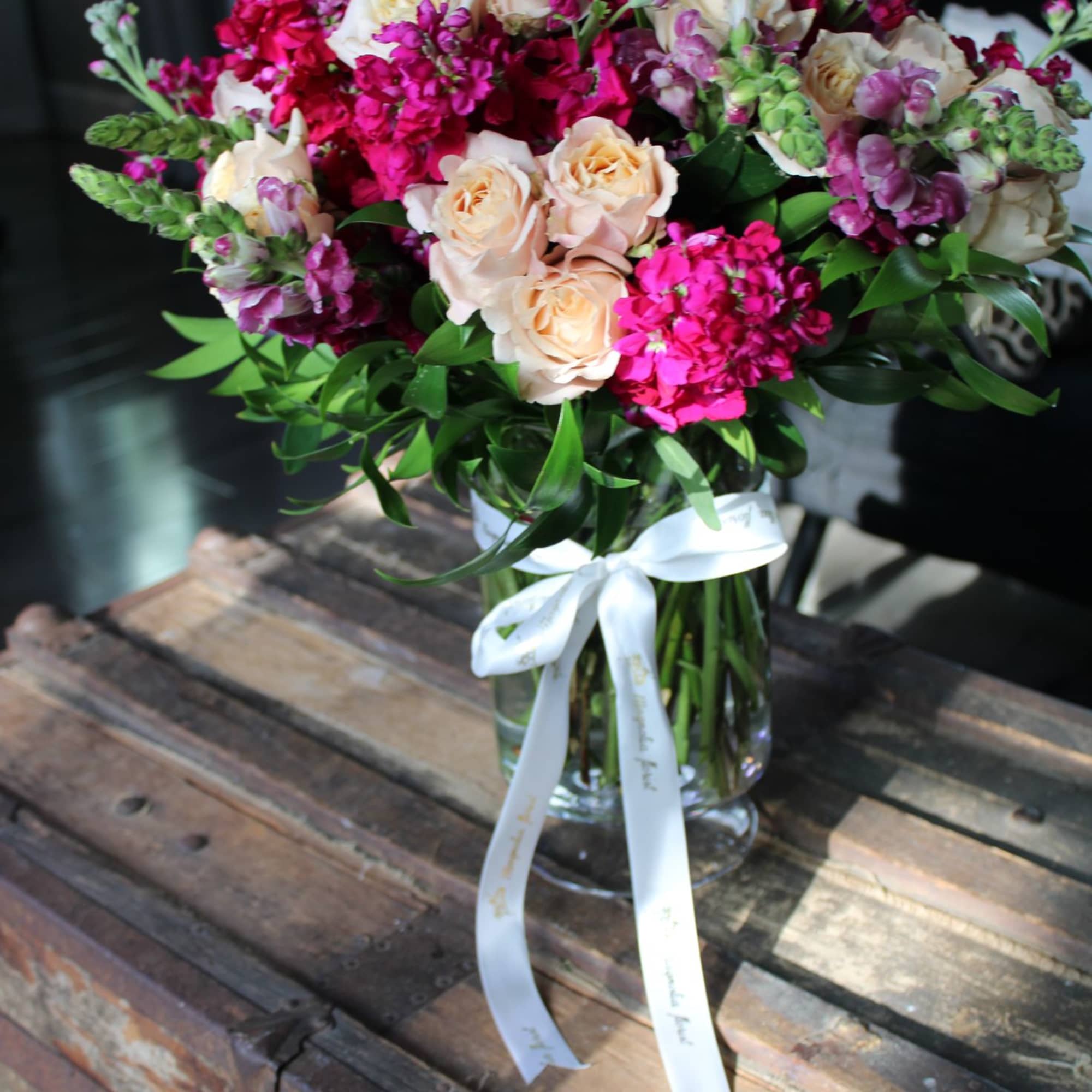 Bouquet of pink and cream roses with magenta flowers in a glass vase