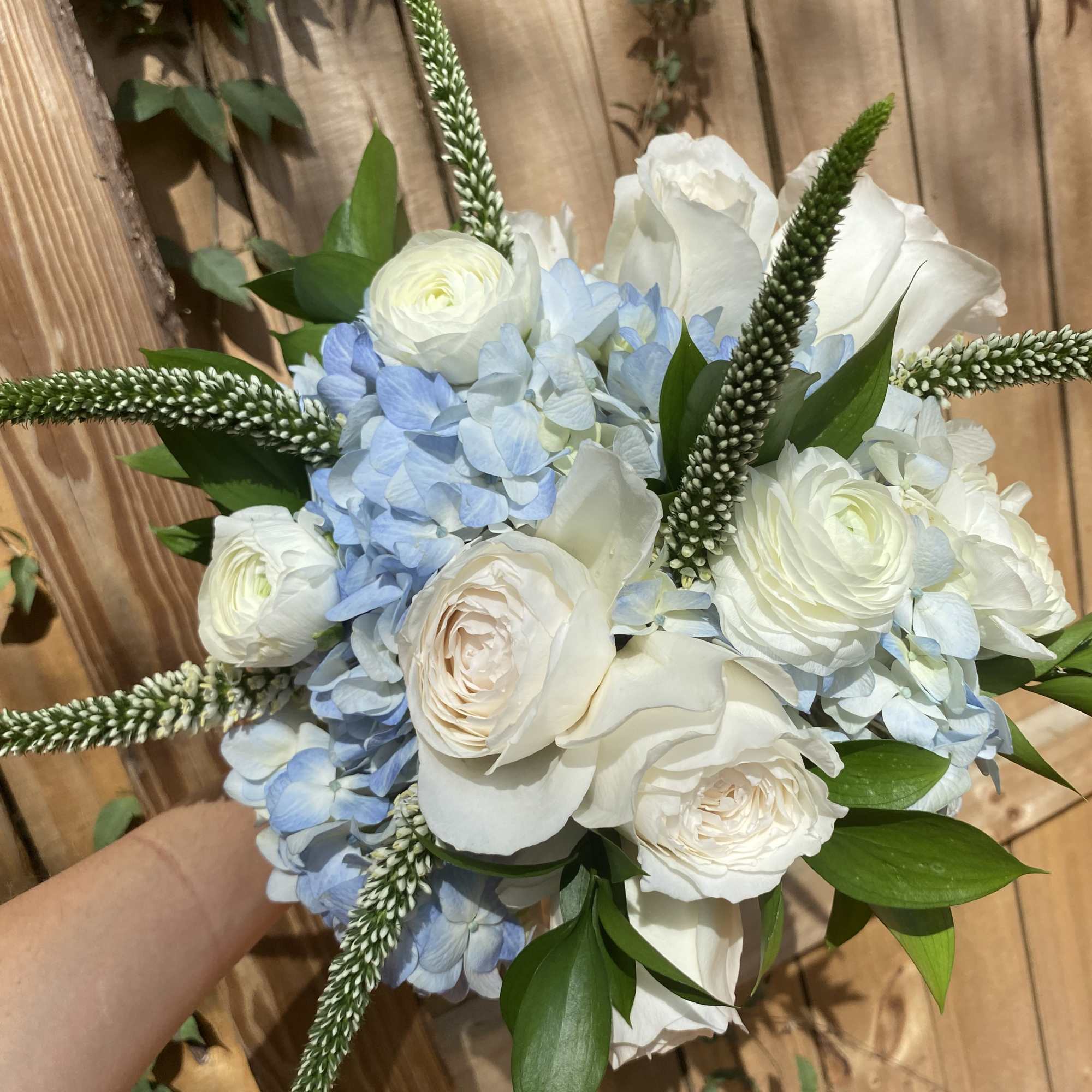 Bouquet of white roses and blue hydrangeas with tall green spikes