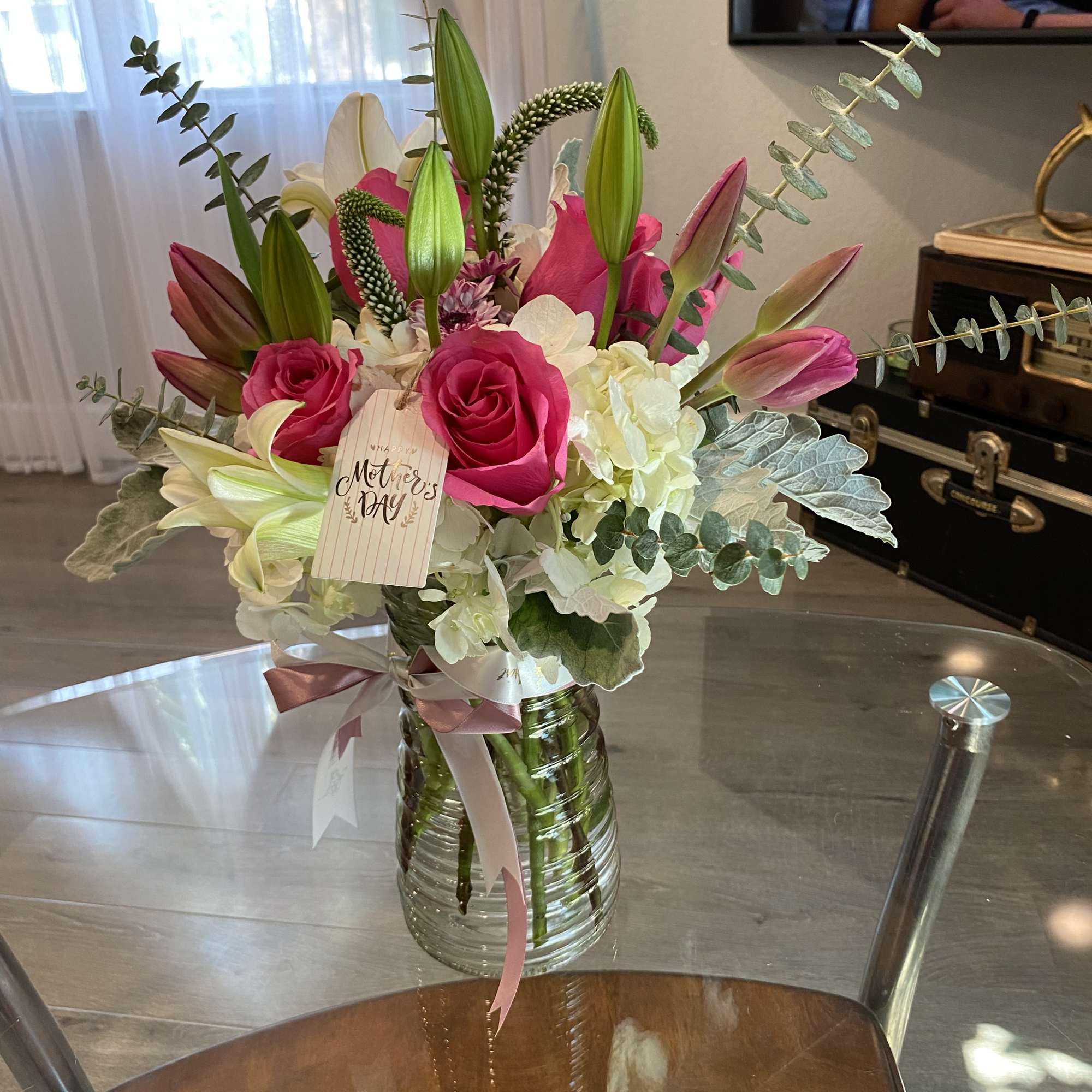 Pink roses and lilies in a glass vase with a Mother's Day tag