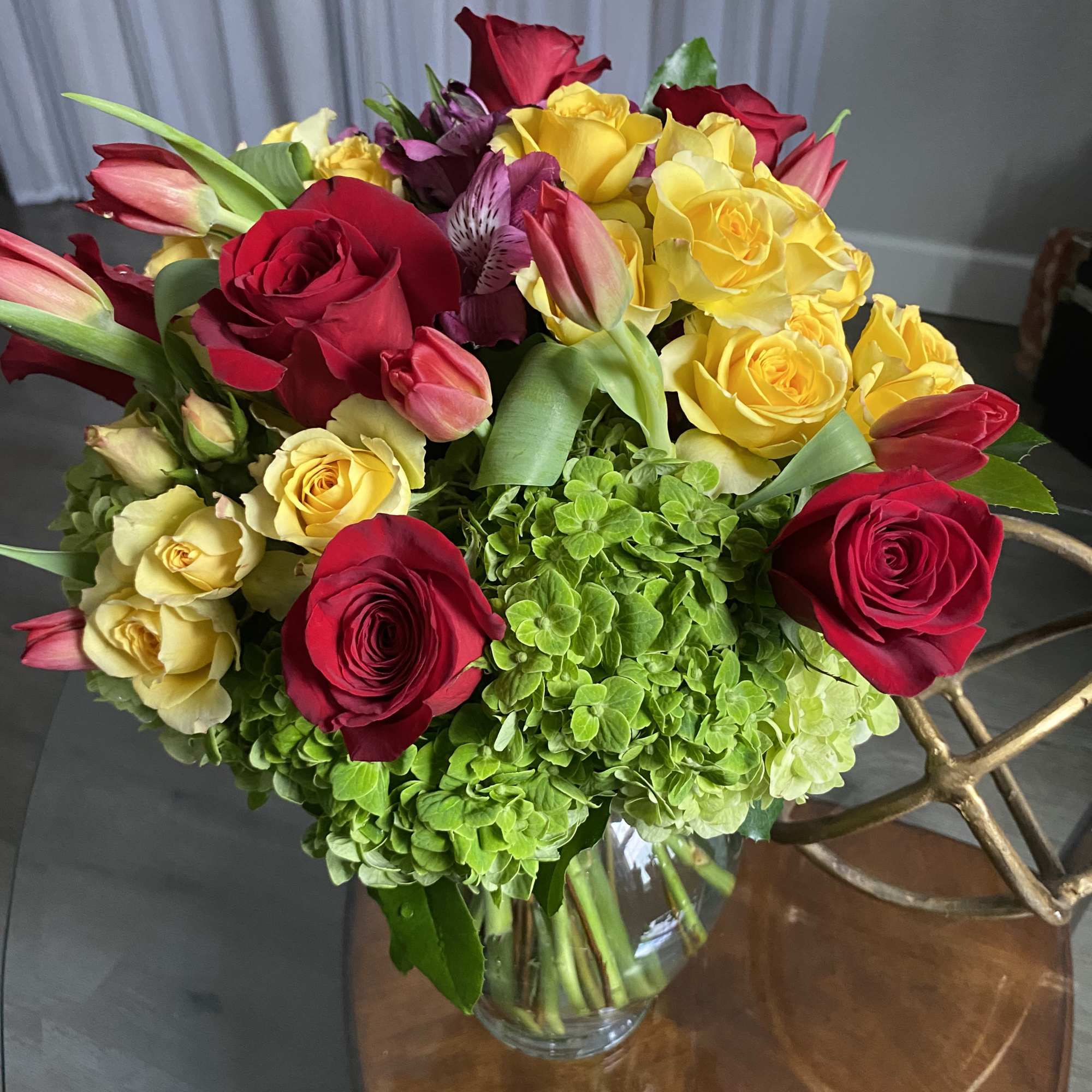 Bouquet of red and yellow roses with pink tulips in a glass vase