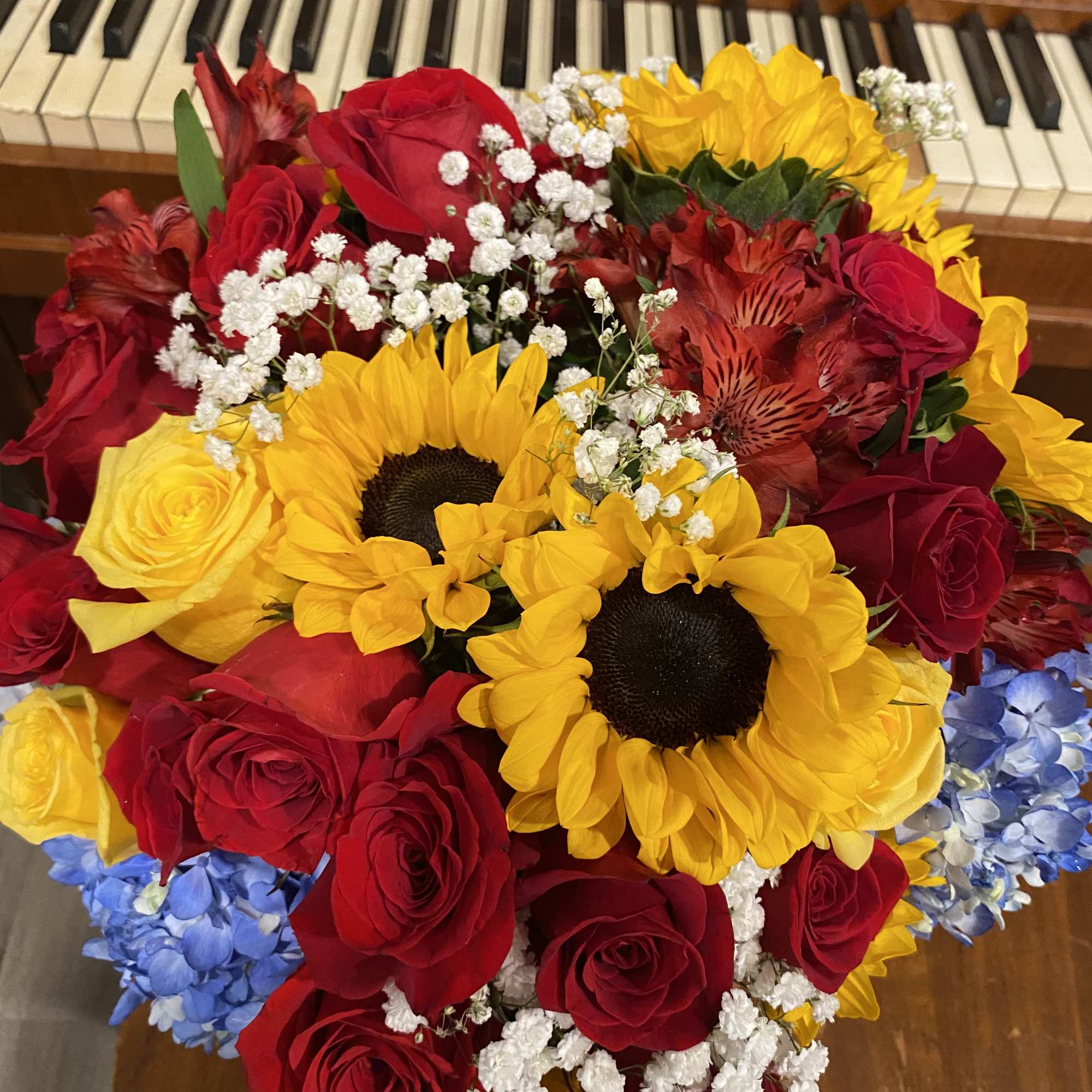 Bouquet of red roses, yellow sunflowers, and blue hydrangeas
