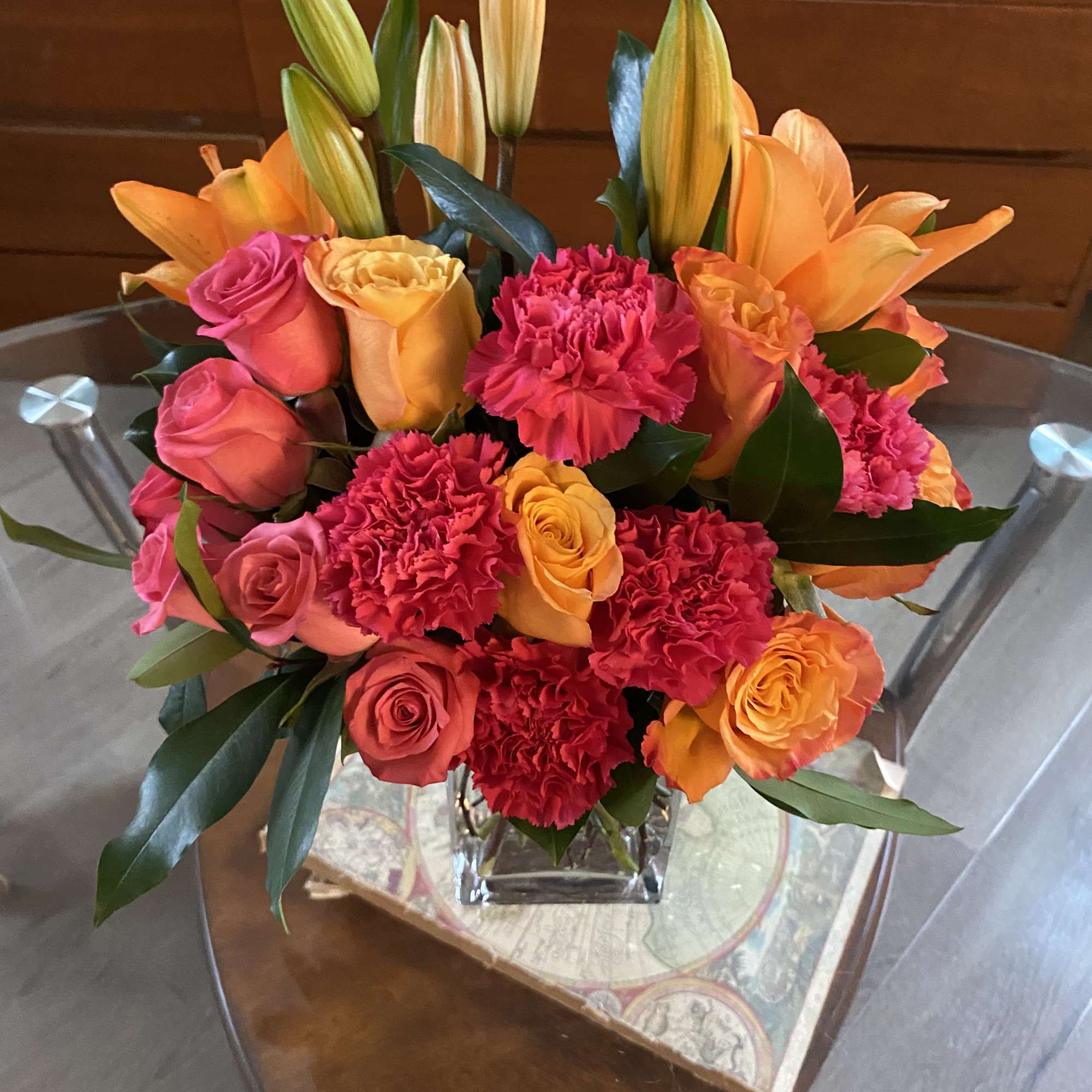 Bouquet of orange lilies, pink roses, and red carnations in a glass vase