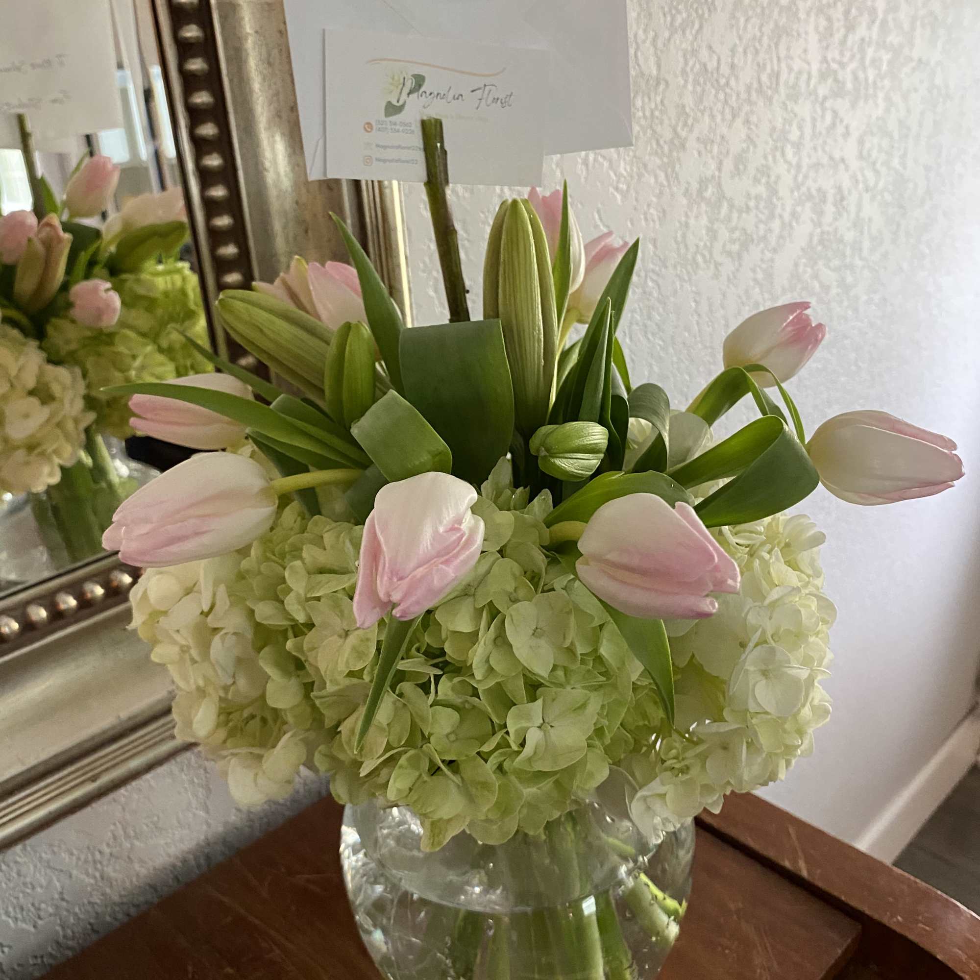 Pink tulips and pale hydrangeas arranged in a clear glass vase
