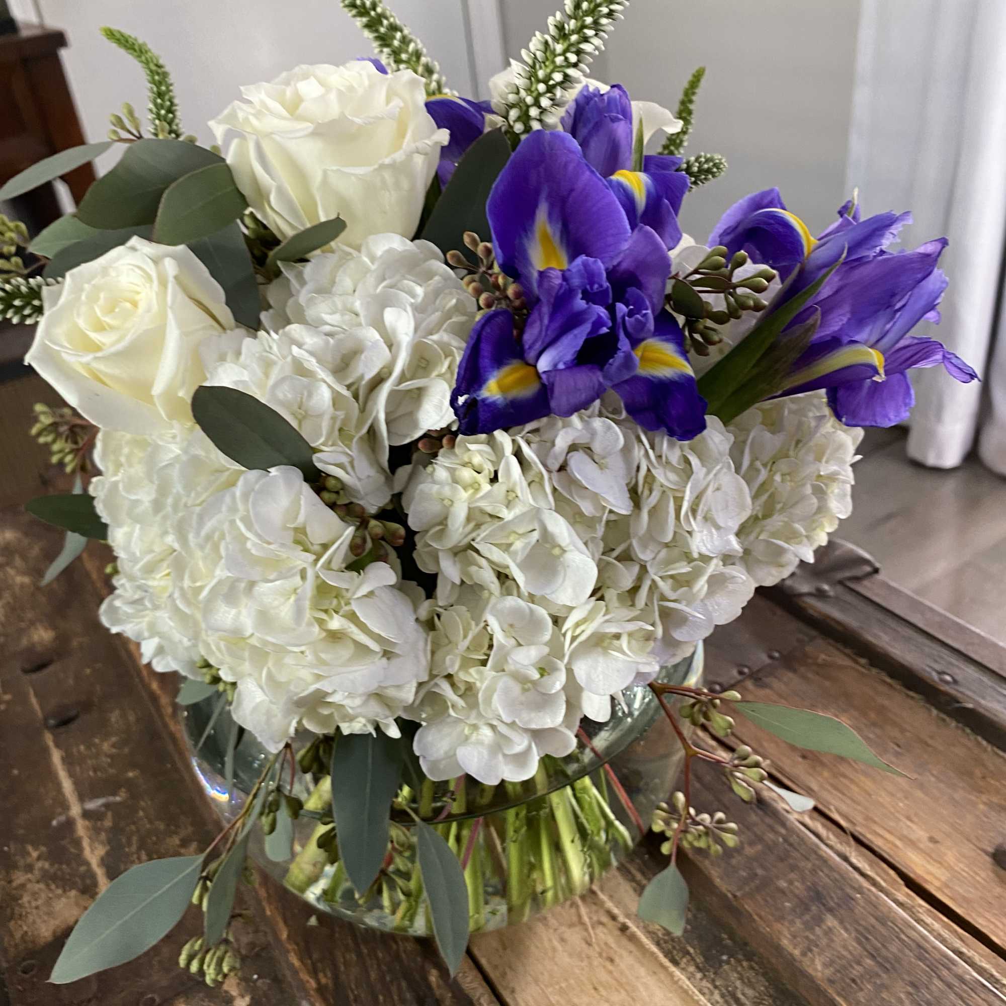 White hydrangeas and purple irises in a glass vase