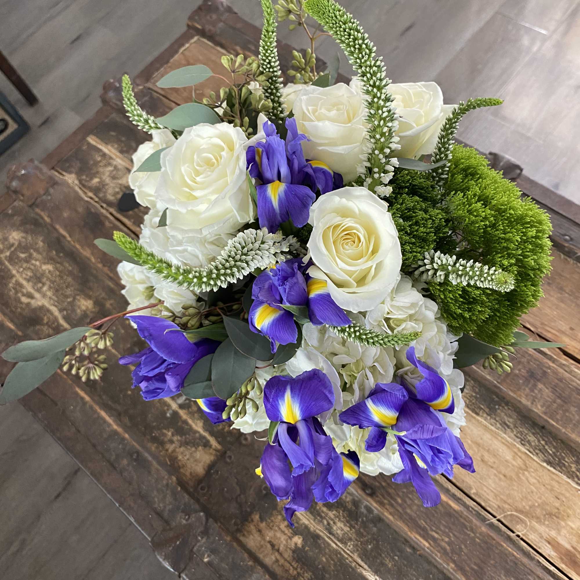 Bouquet of white roses and purple irises with green accents