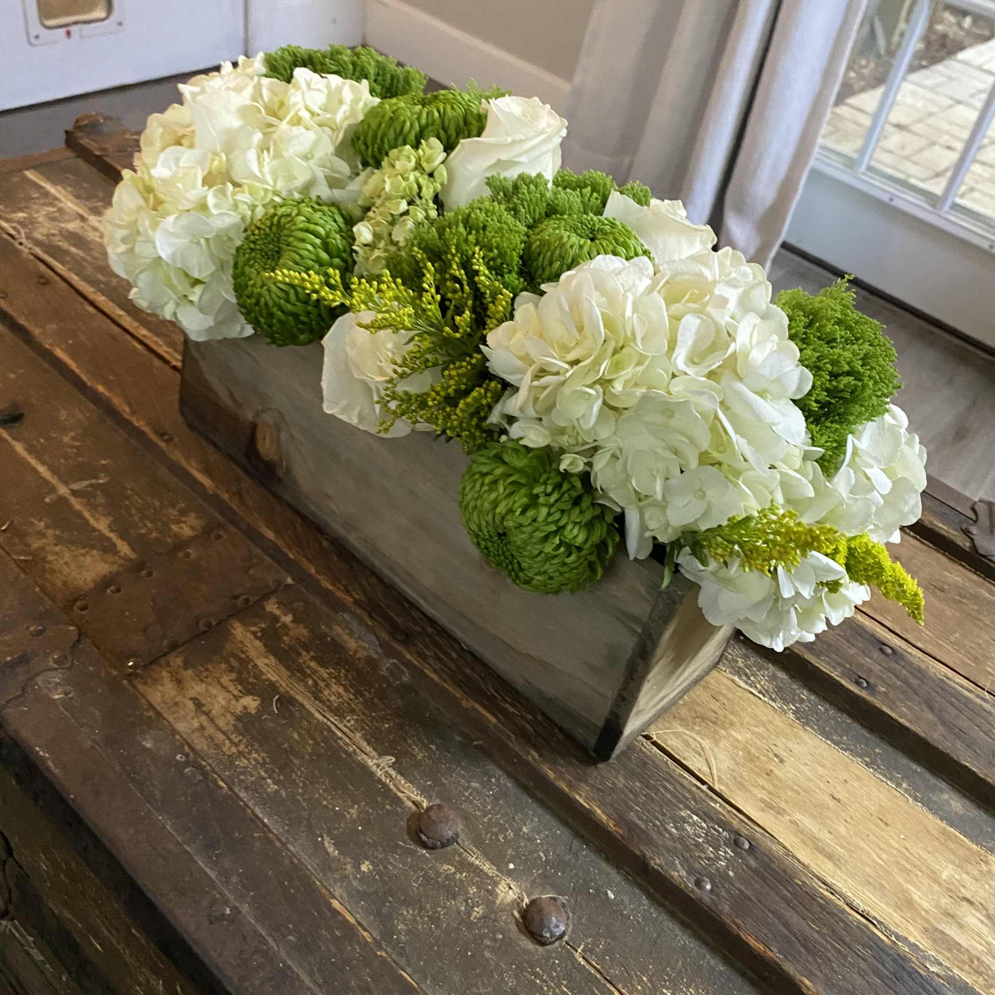 White and green floral arrangement in a rectangular wooden box