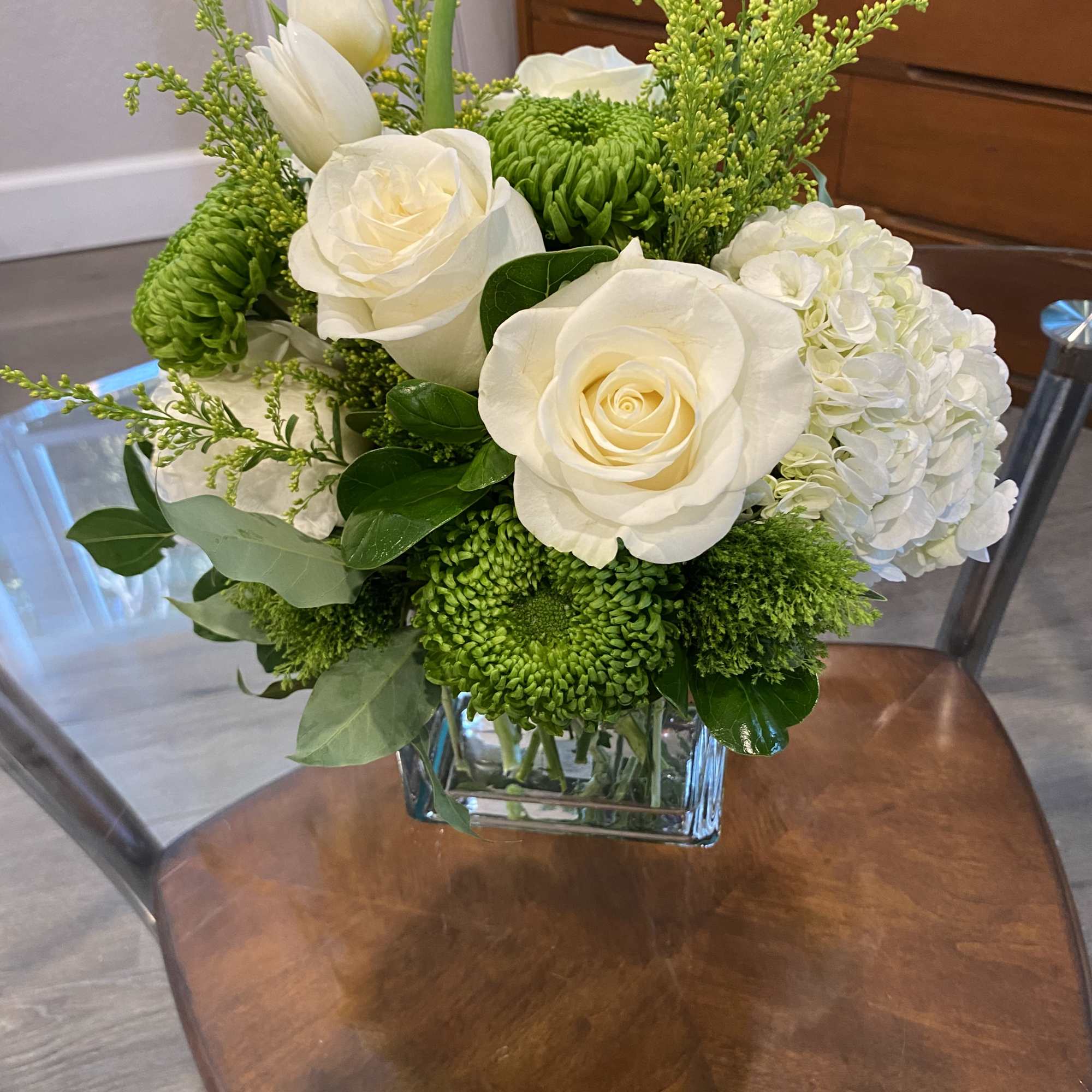 White roses and green chrysanthemums in a square glass vase