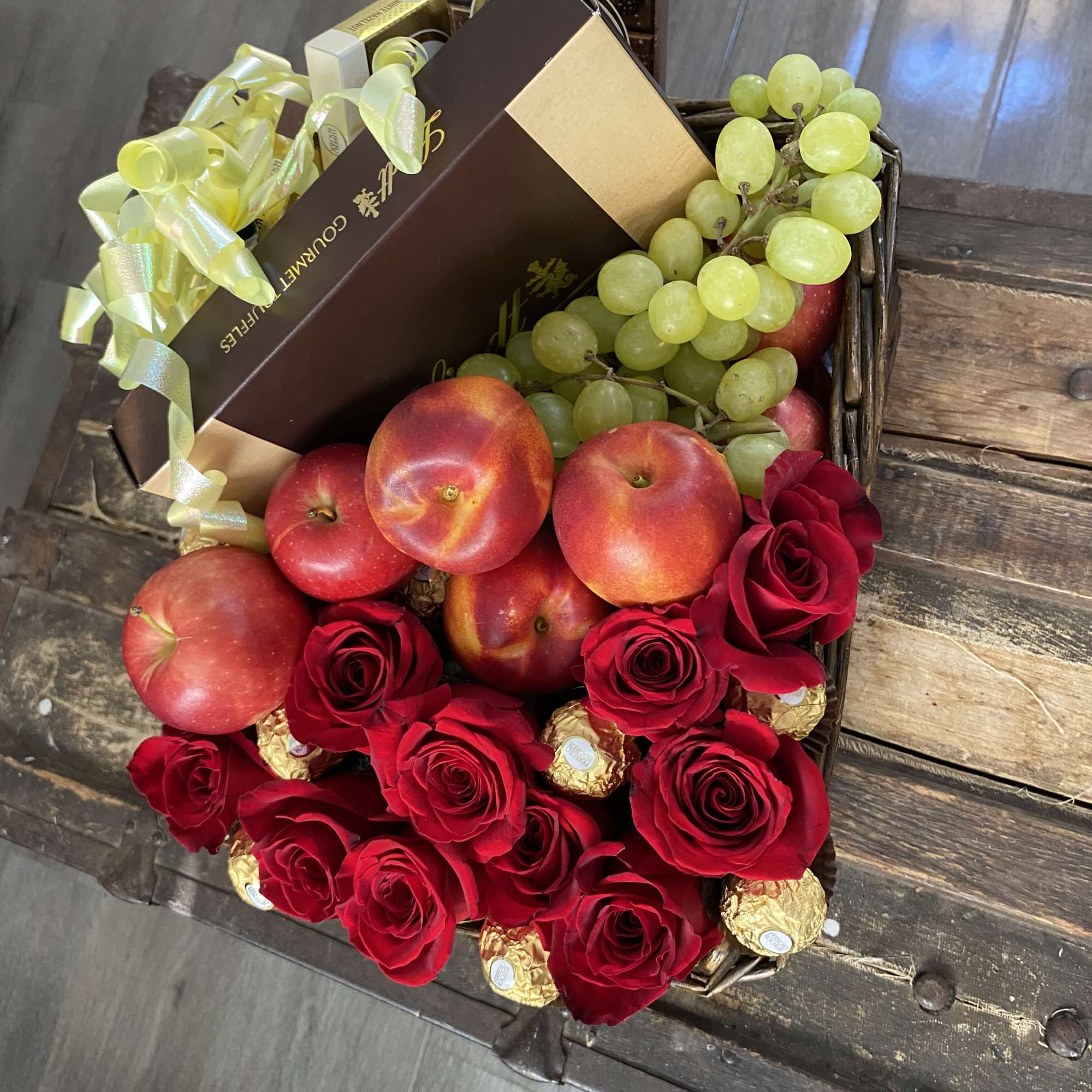 Gift basket with red roses, fruit, and chocolates