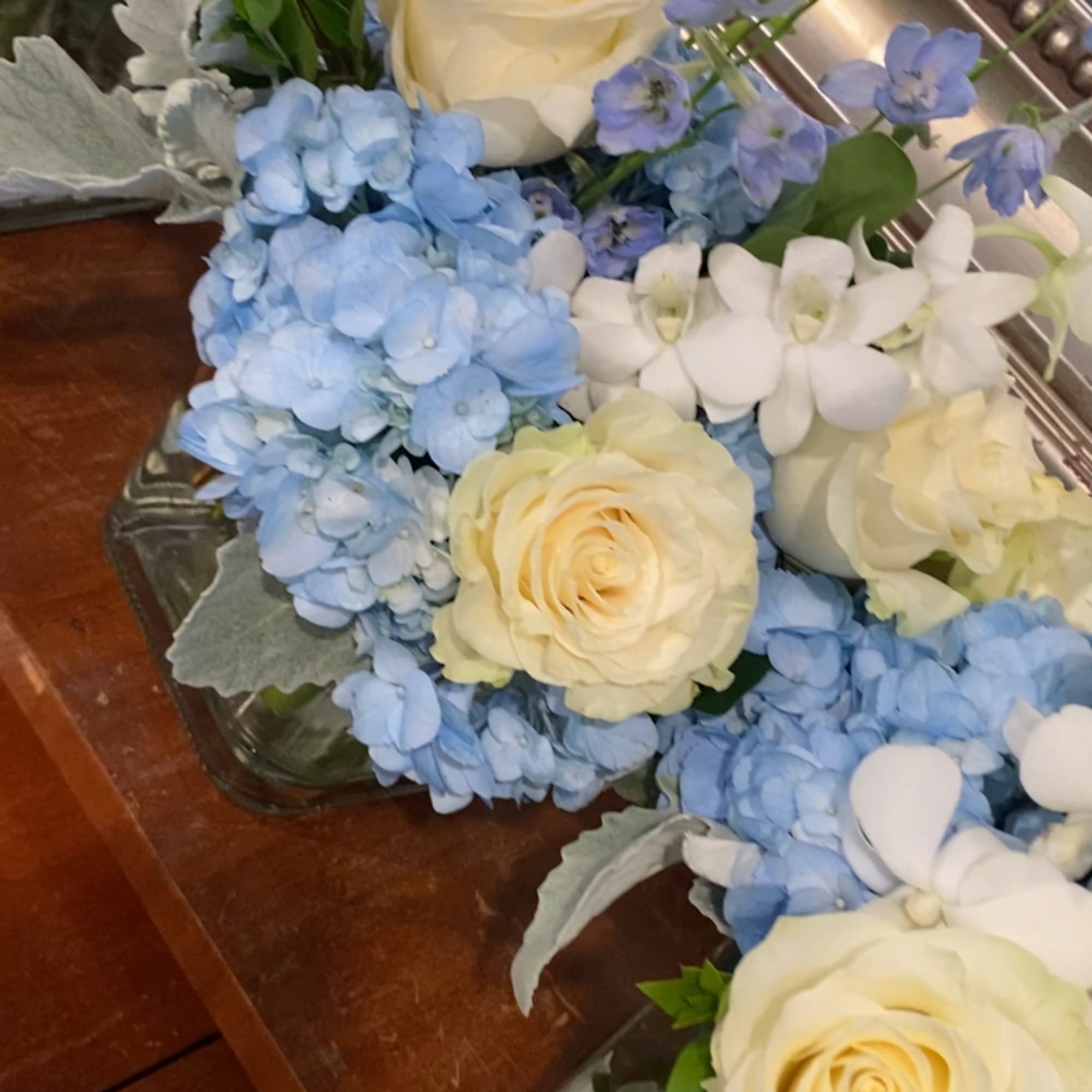 Cream roses and blue hydrangeas arranged in glass containers