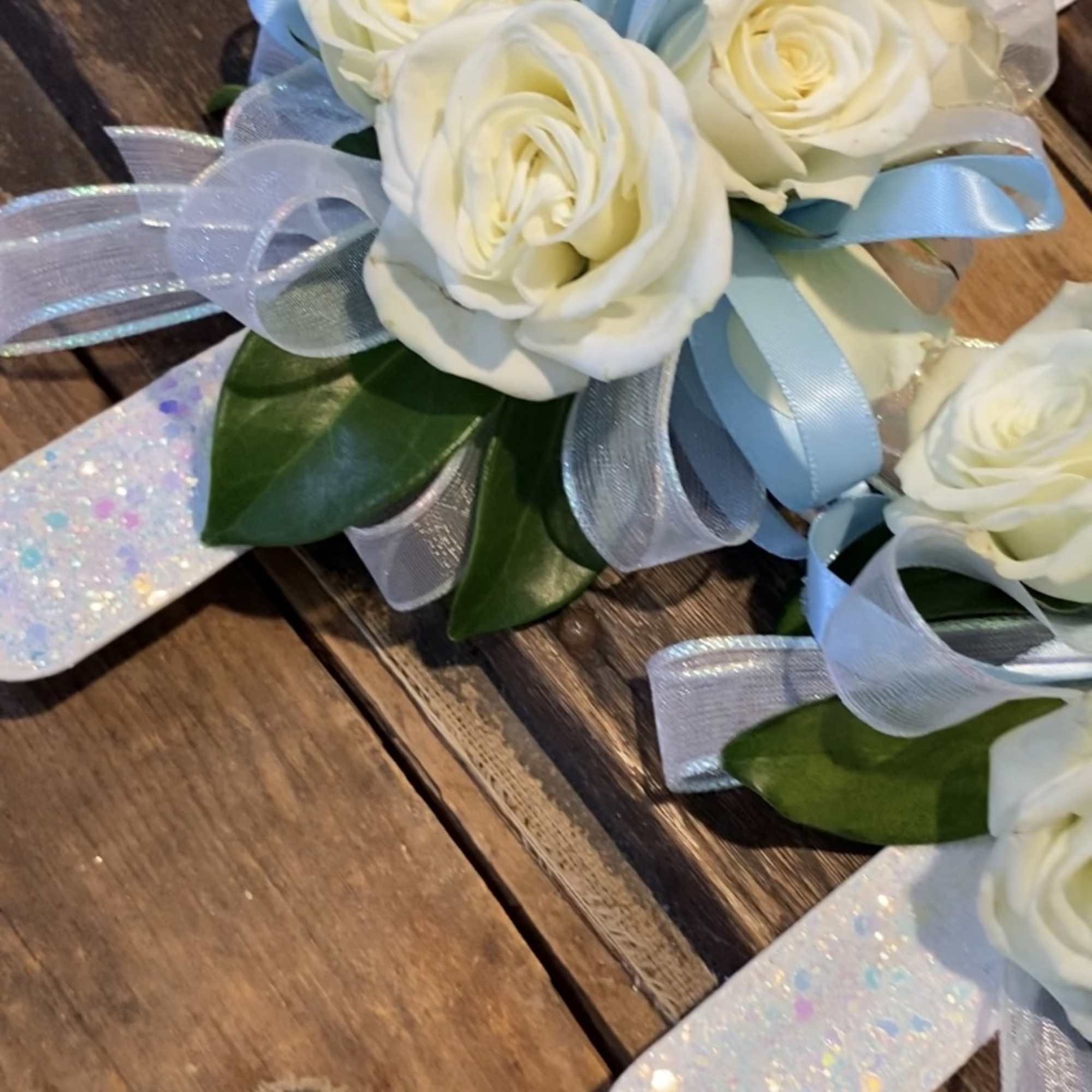 White rose corsage with blue ribbon and glittery wrap