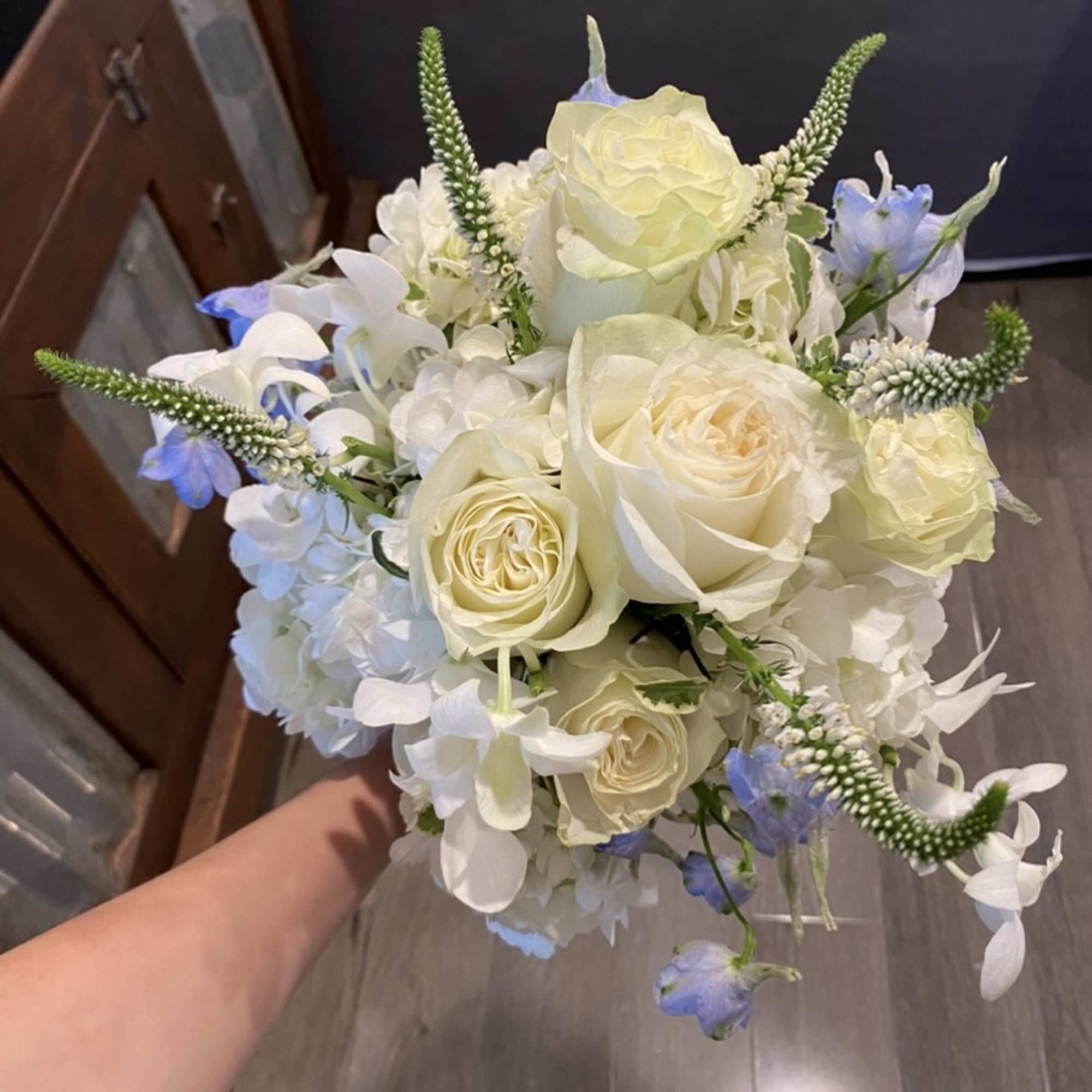 Handheld bouquet of white roses and pale blue flowers