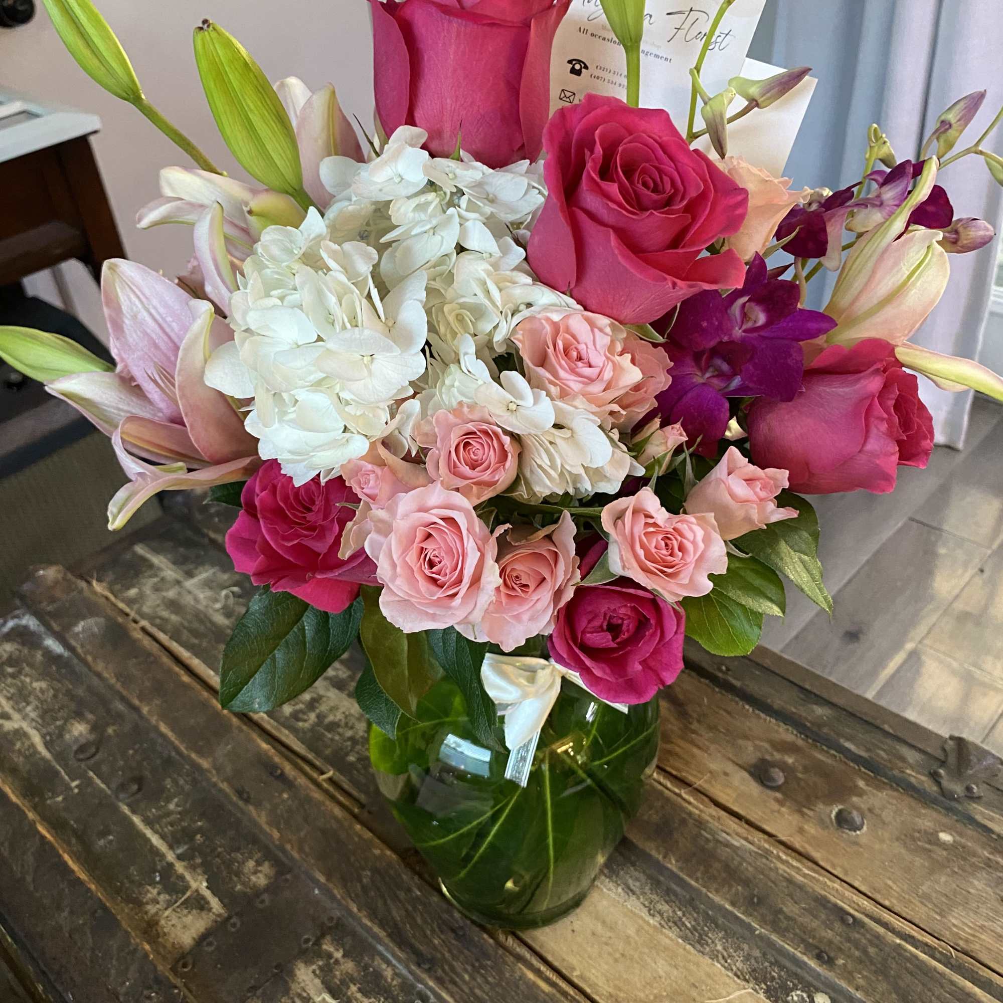 Bouquet of pink roses, white hydrangea, and lilies in a glass vase