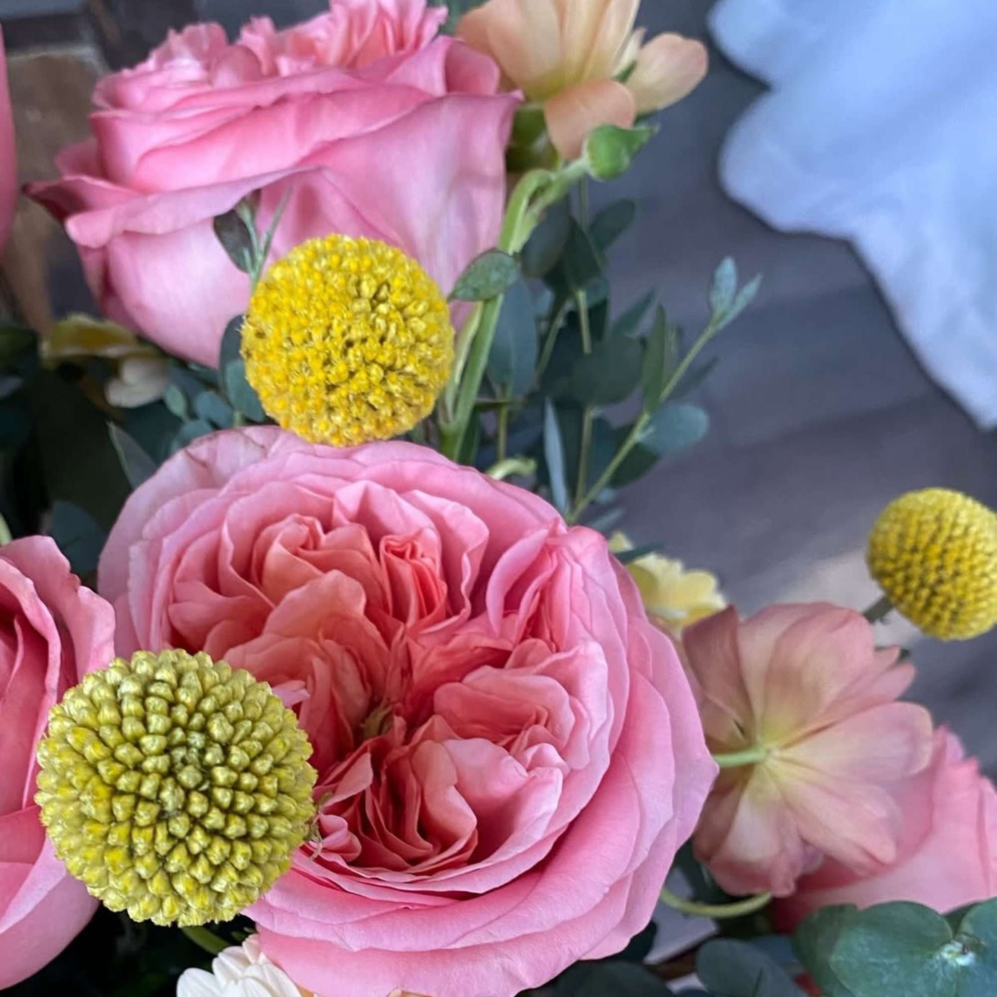 Pink roses with yellow pom-pom flowers and pale blooms in a bouquet