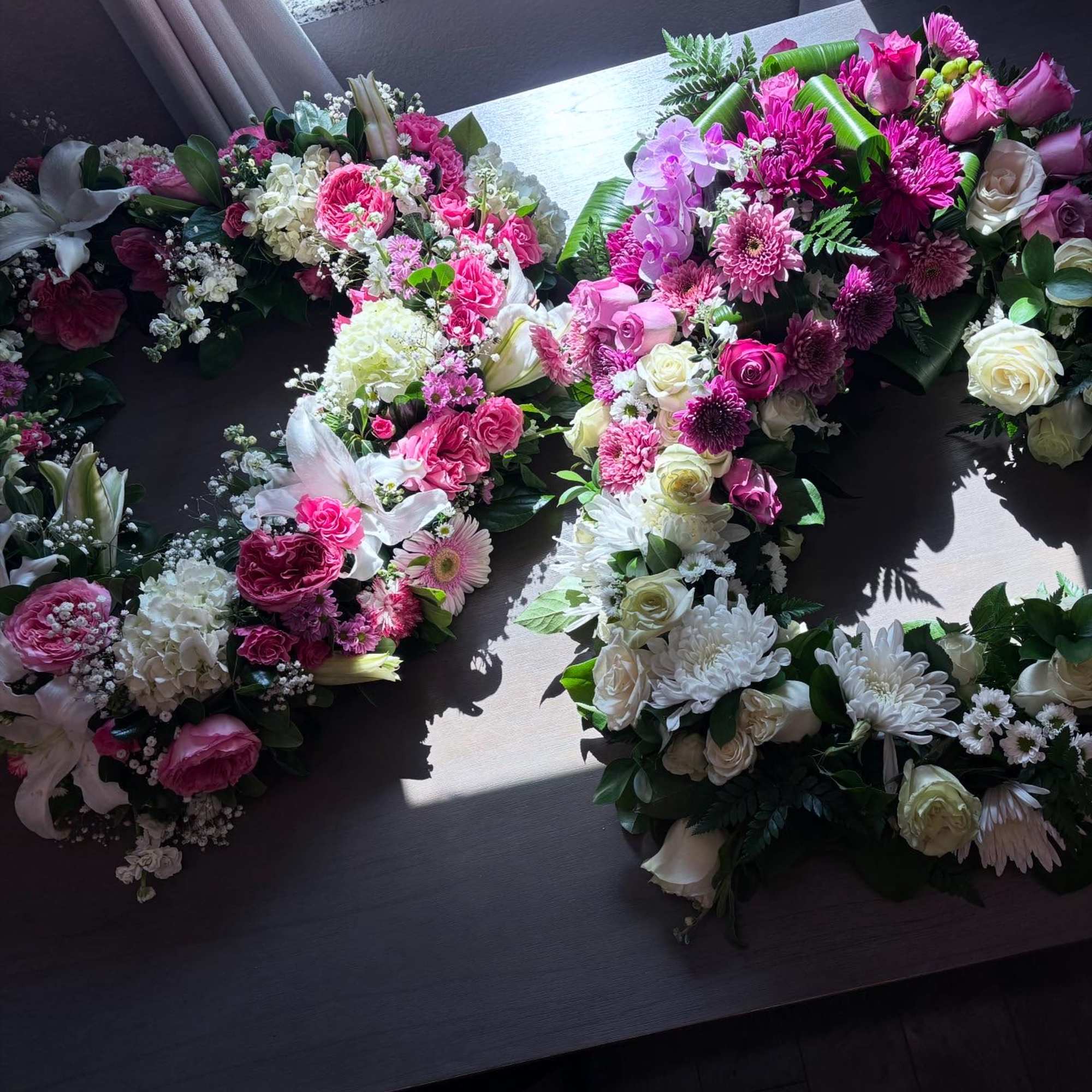 Pink and white floral letter arrangements on a table