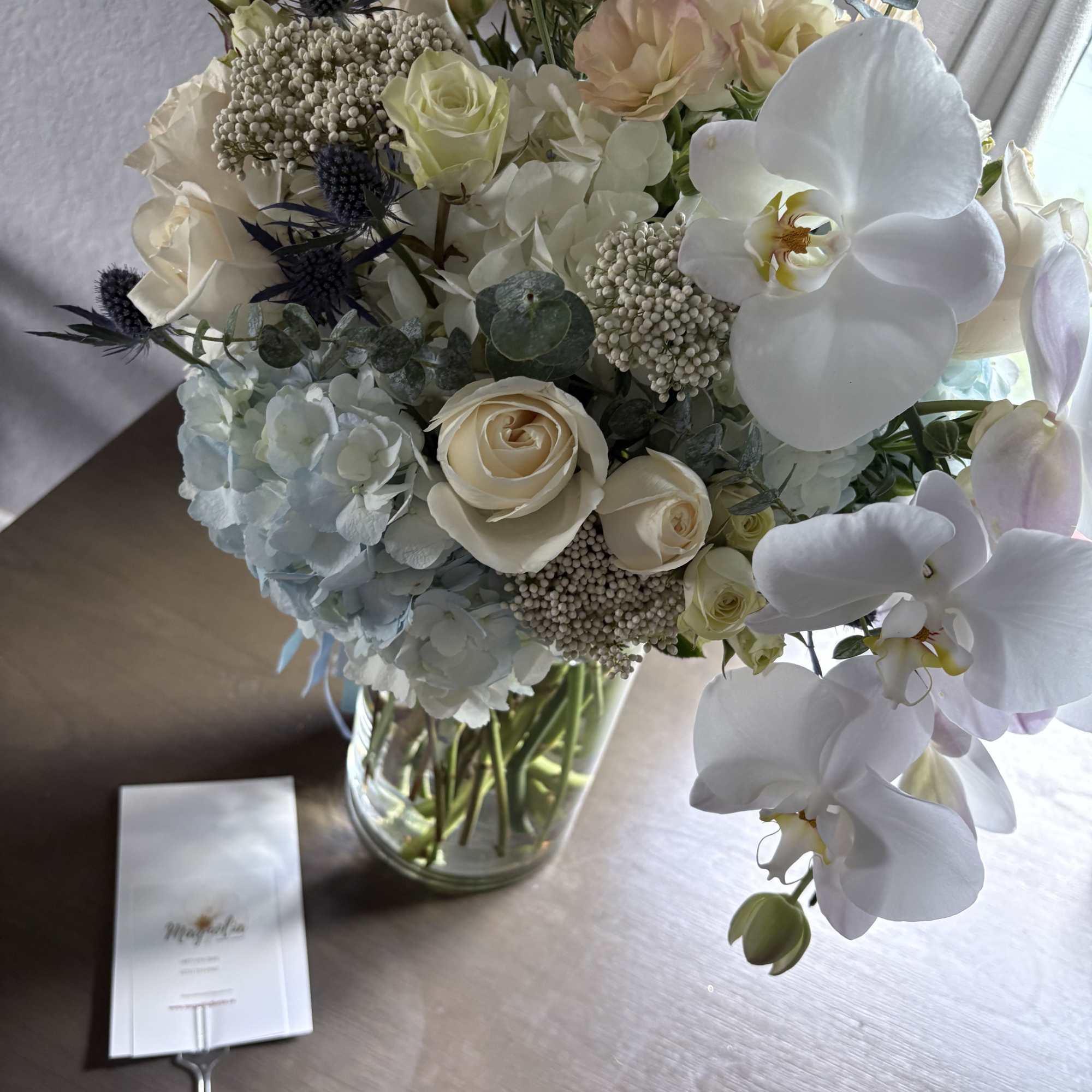 White and cream bouquet with orchids and roses in a glass vase
