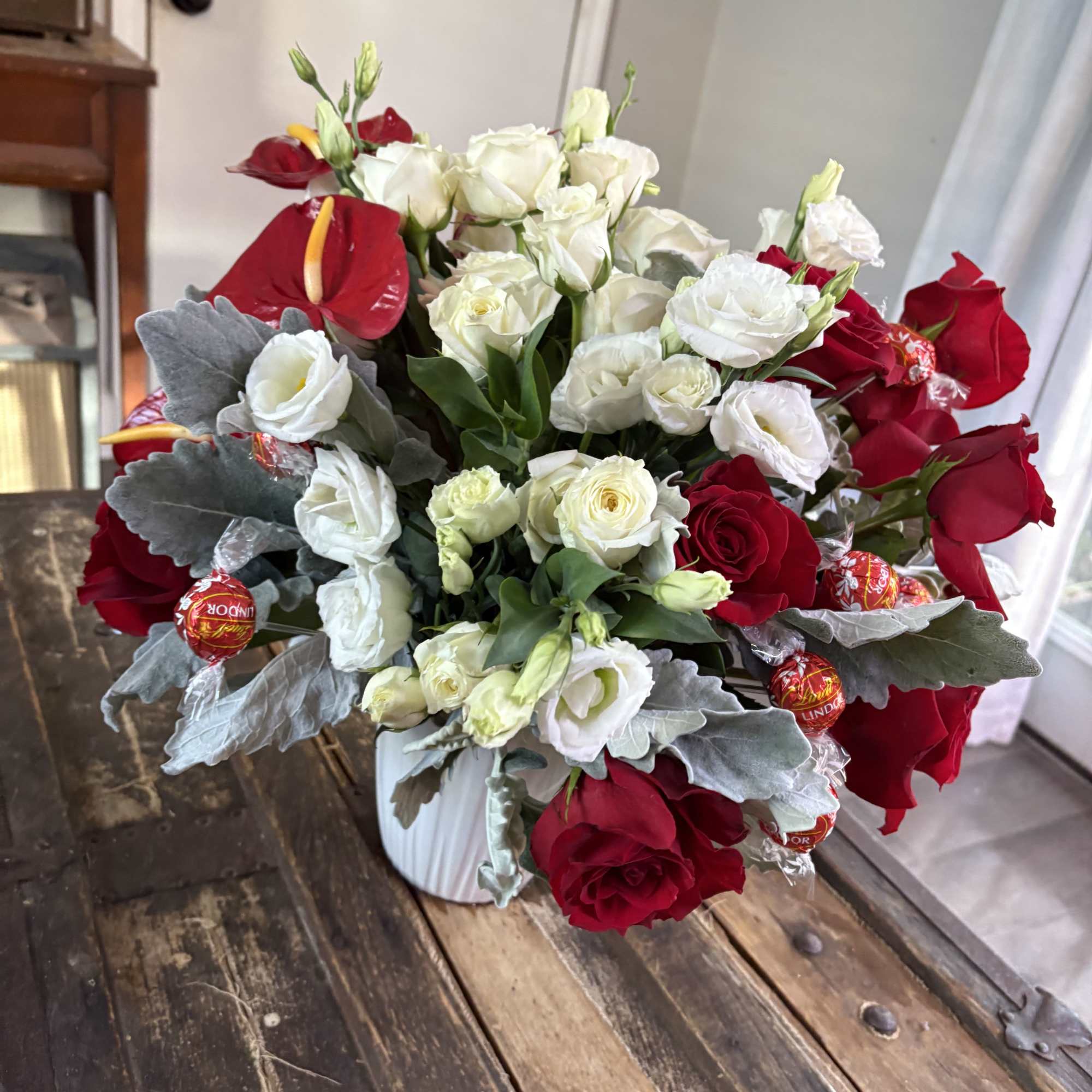 Bouquet of red roses and white lisianthus in a white vase