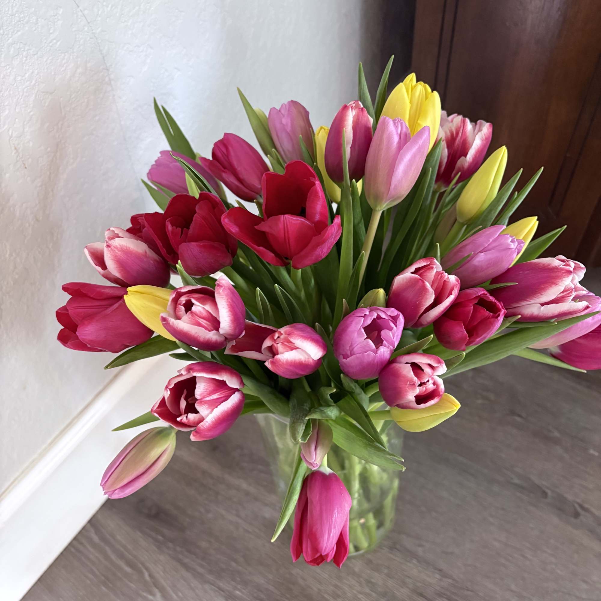 Bouquet of pink, red, and yellow tulips in a clear glass vase
