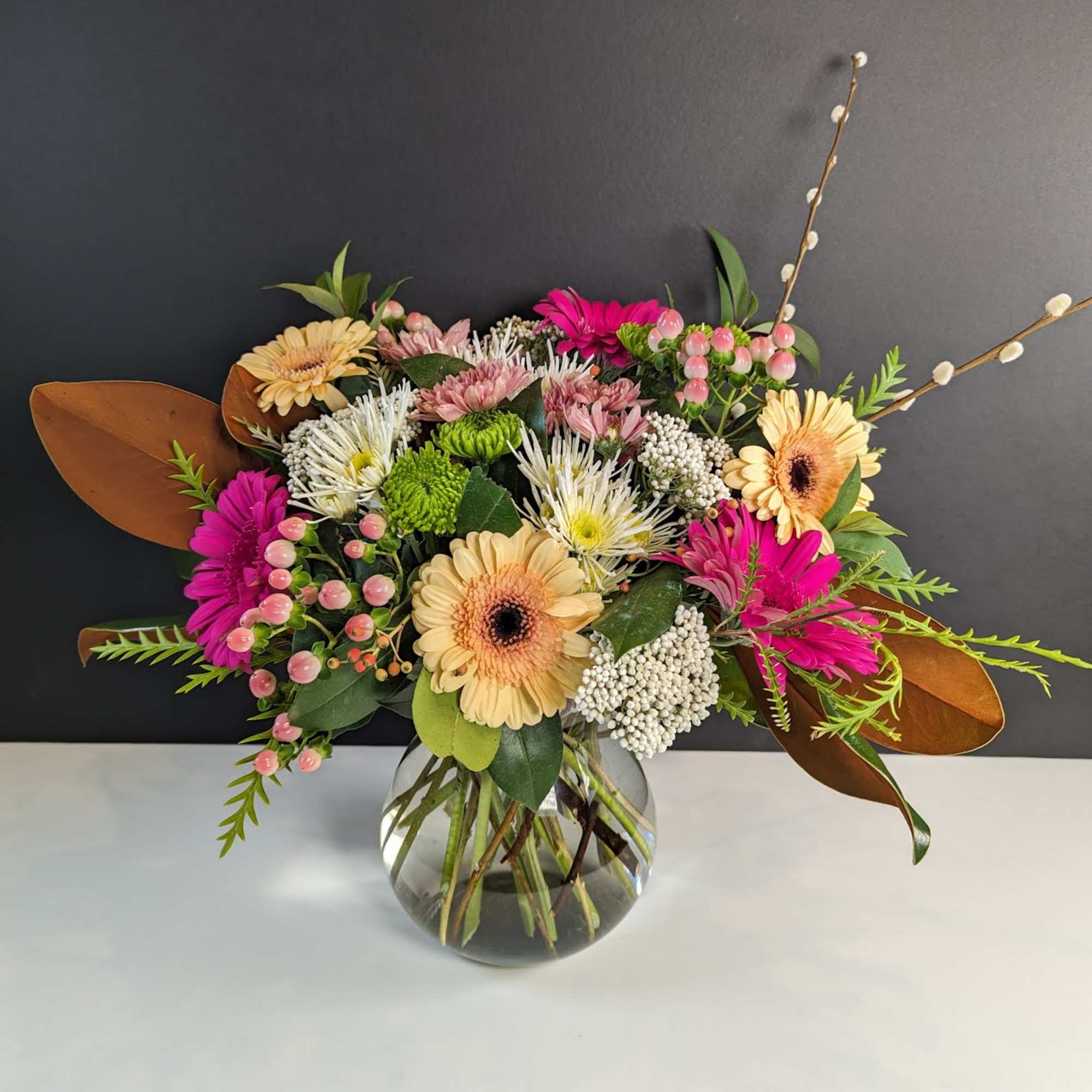 Mixed bouquet of gerbera daisies and chrysanthemums in a glass vase