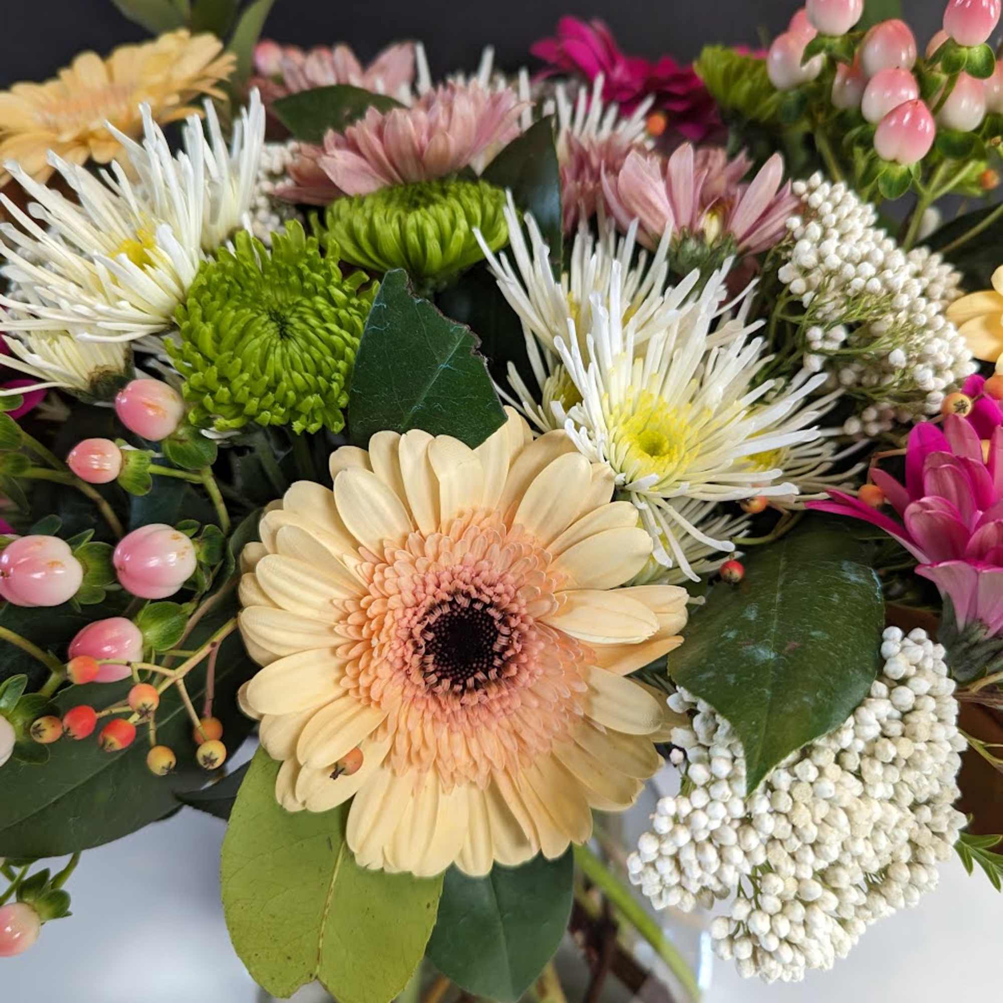 Mixed bouquet of gerbera daisies and chrysanthemums in a glass vase, photo 2 of 3